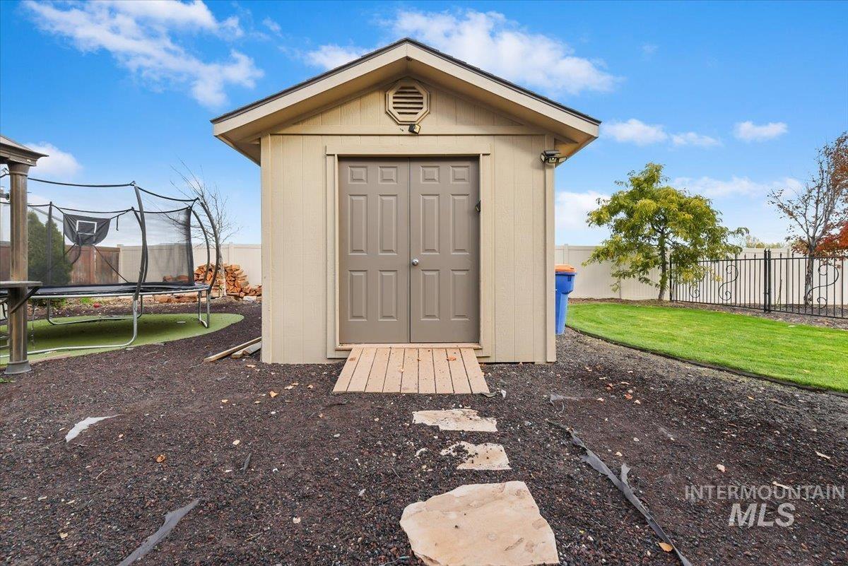 View of shed featuring a trampoline and a fenced backyard