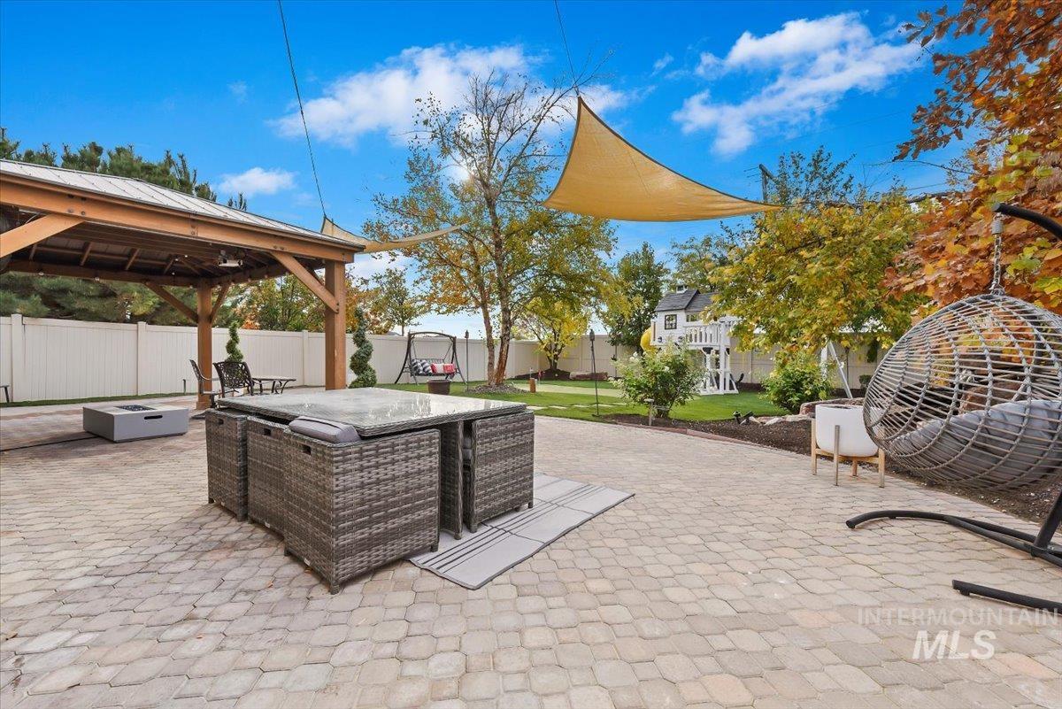 Fenced backyard featuring a patio, outdoor dining area, a gazebo, and a playground