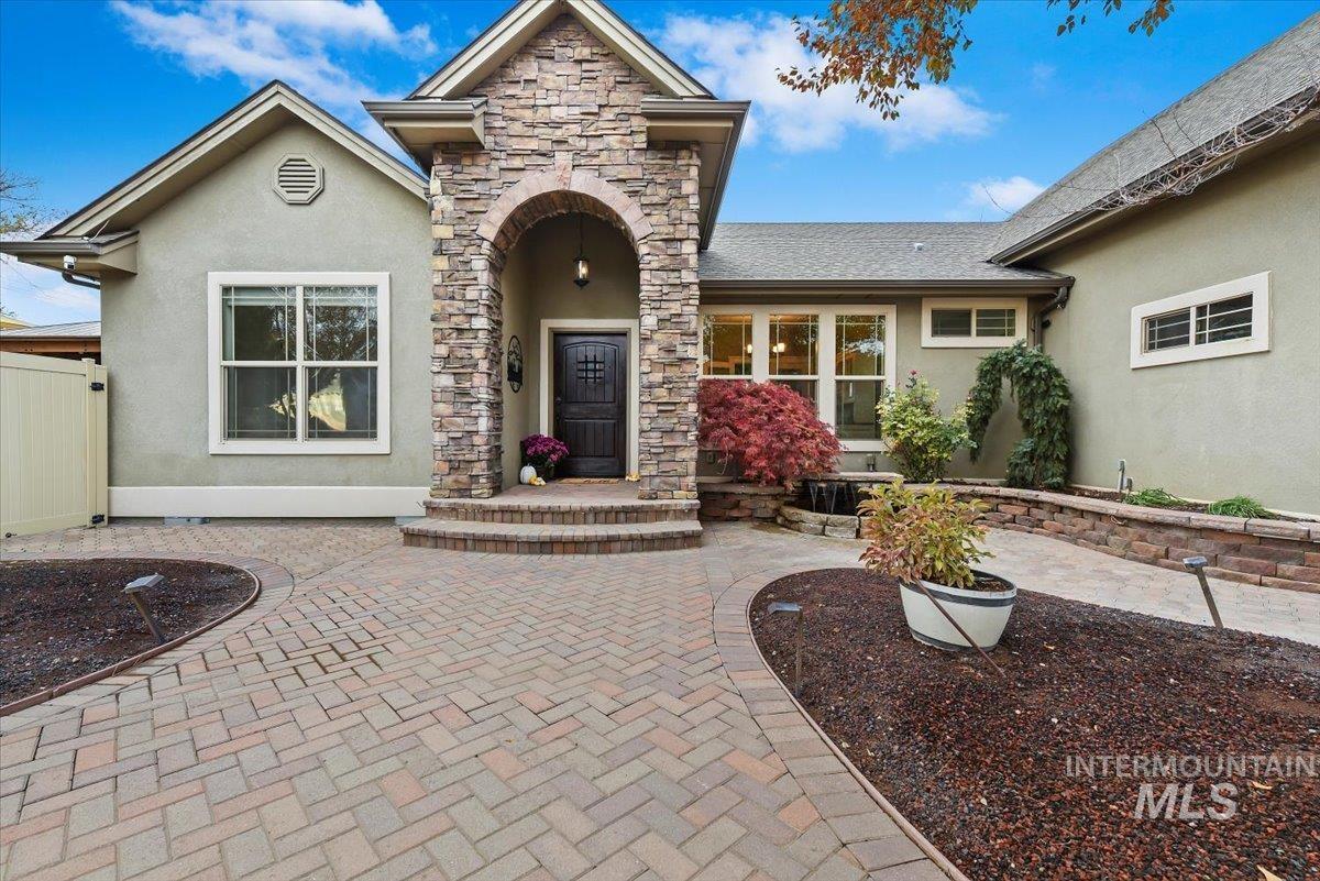 View of exterior entry with stucco siding and stone siding