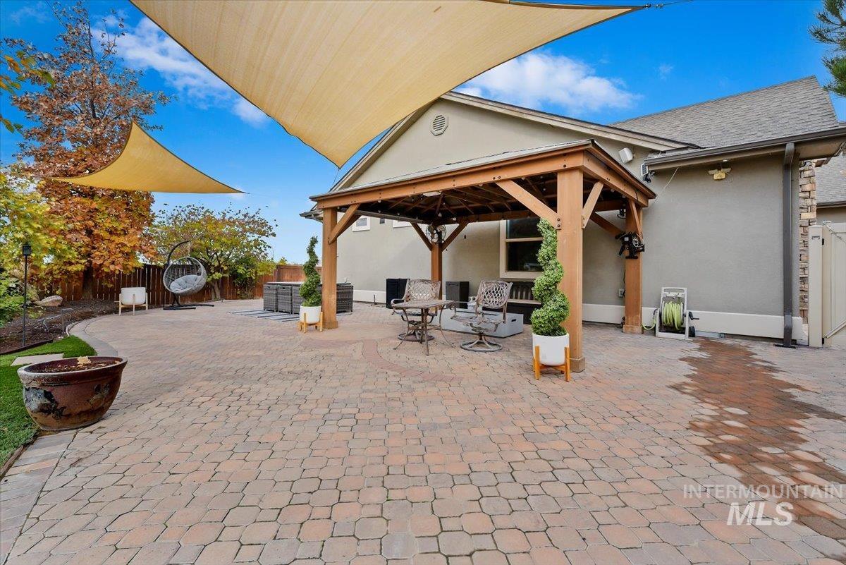 Fenced backyard with a patio area with gorgeous pavers, play equipment, and putting green to practice your game.
