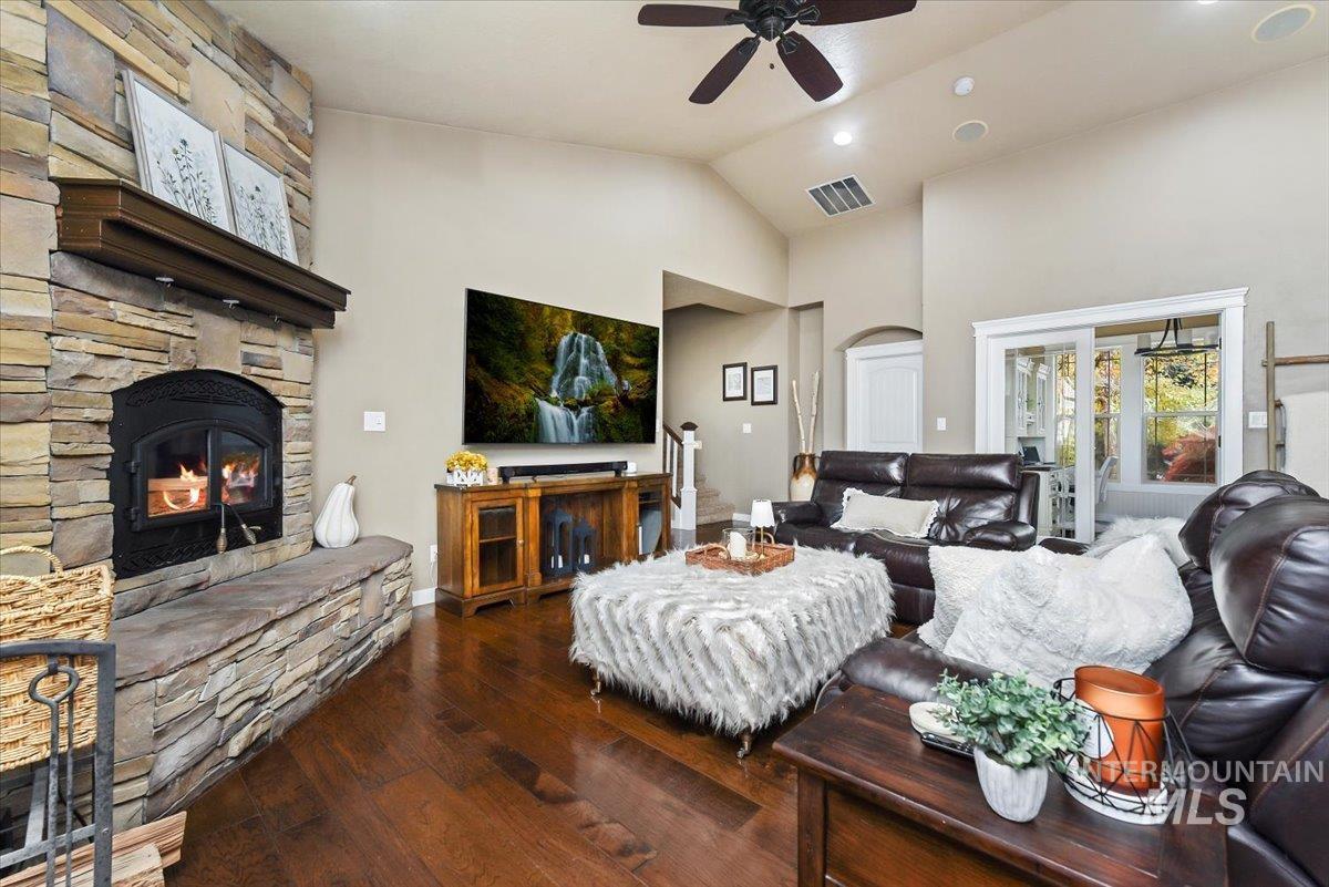 Living room featuring Georgeous wood-style flooring, vaulted ceiling, ceiling fan, a cozy fireplace and lots of windows for natural lighting and view of the surrounding area.