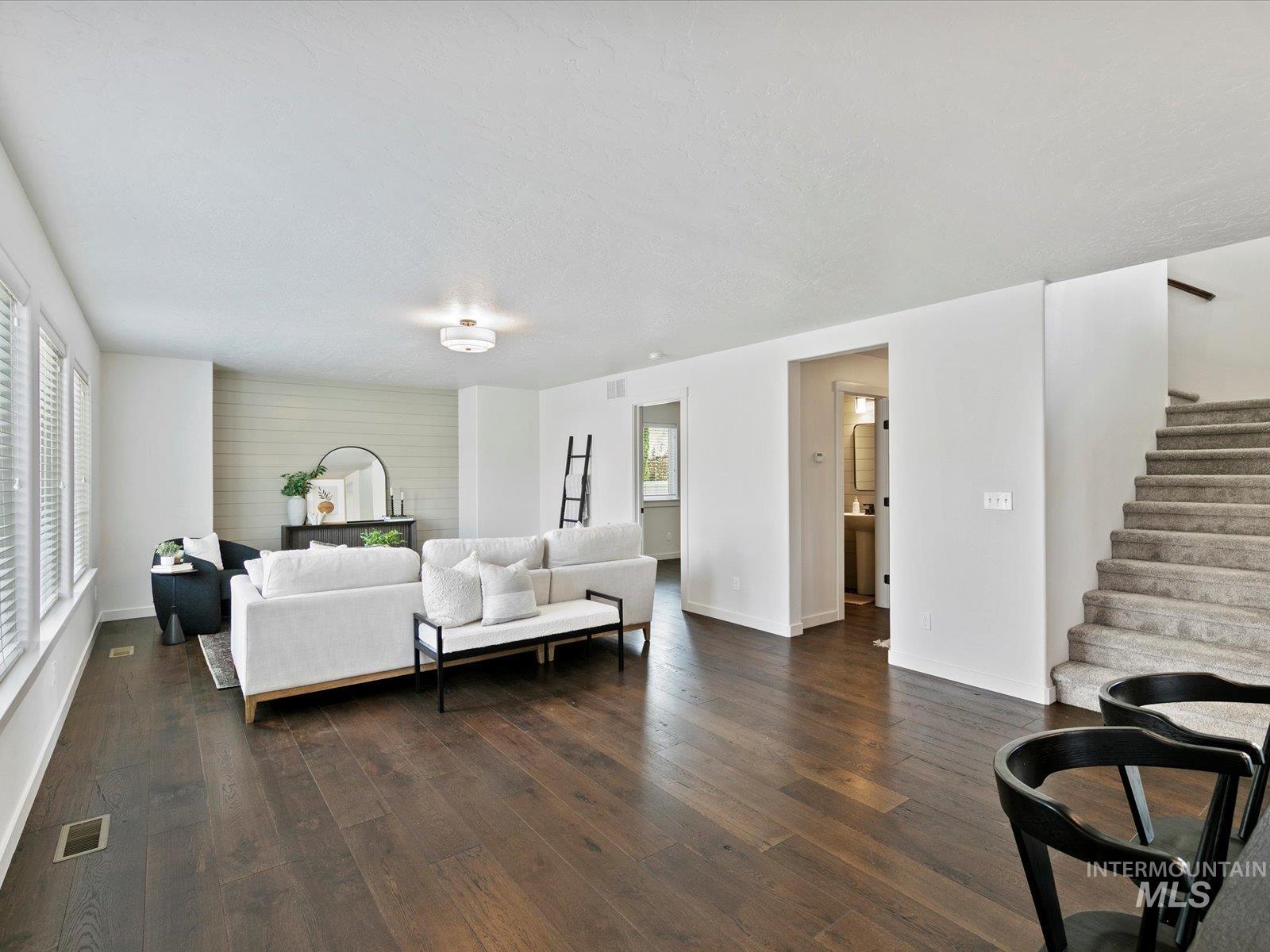 Living room with dark wood finished floors, plenty of natural light, and stairway