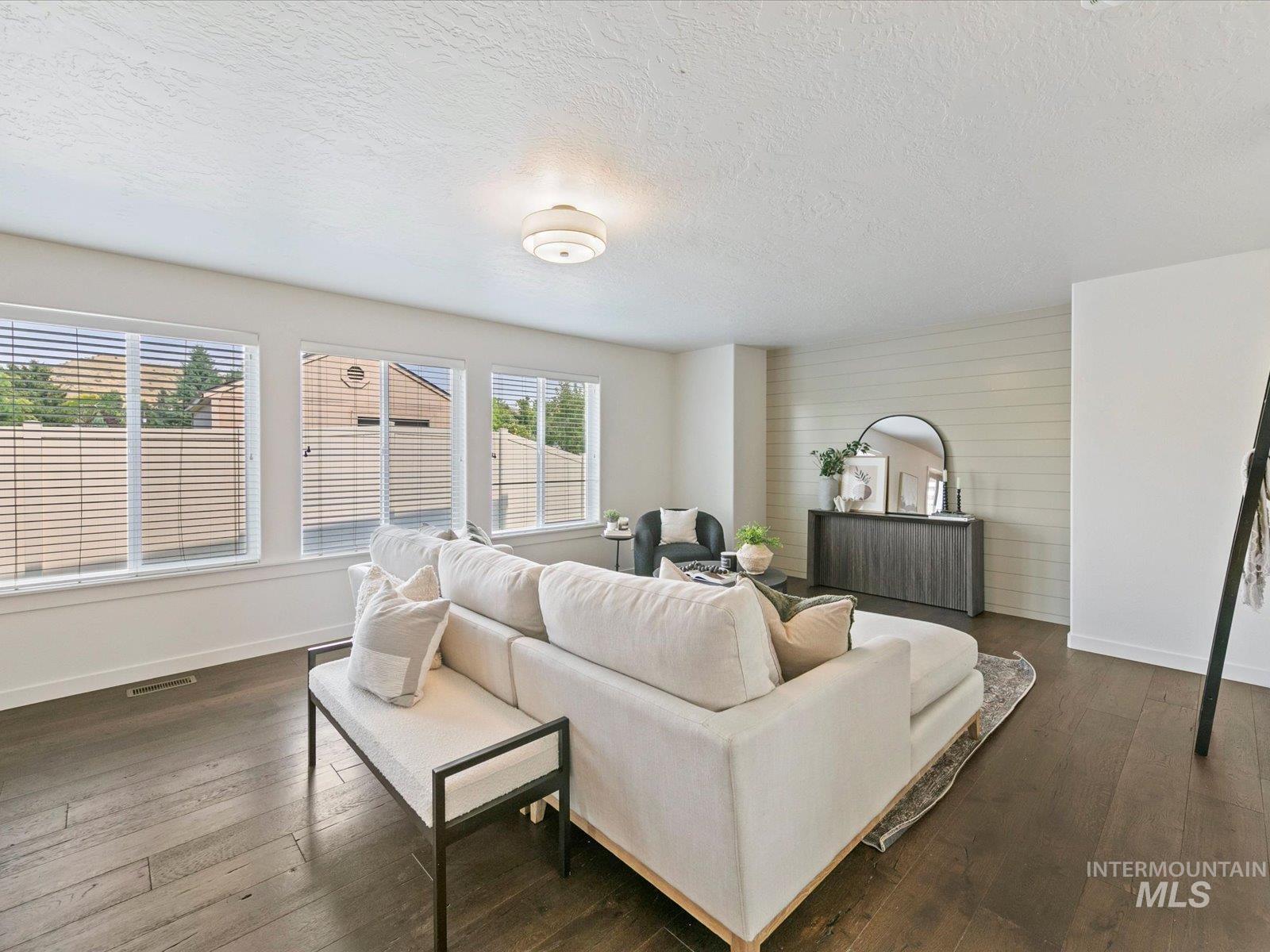 Living room featuring a textured ceiling and dark wood-style floors