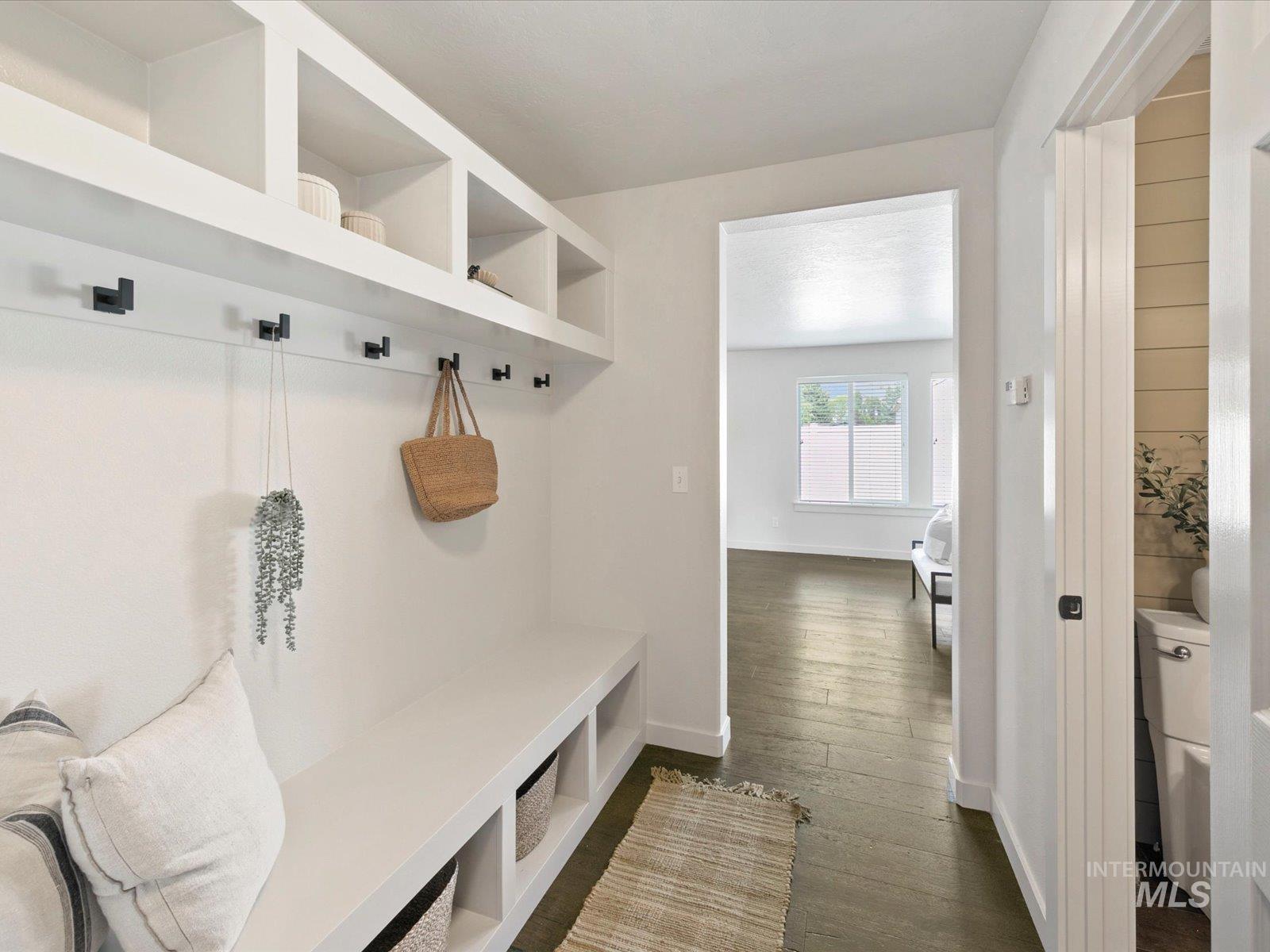 Mudroom featuring dark wood-style floors and baseboards