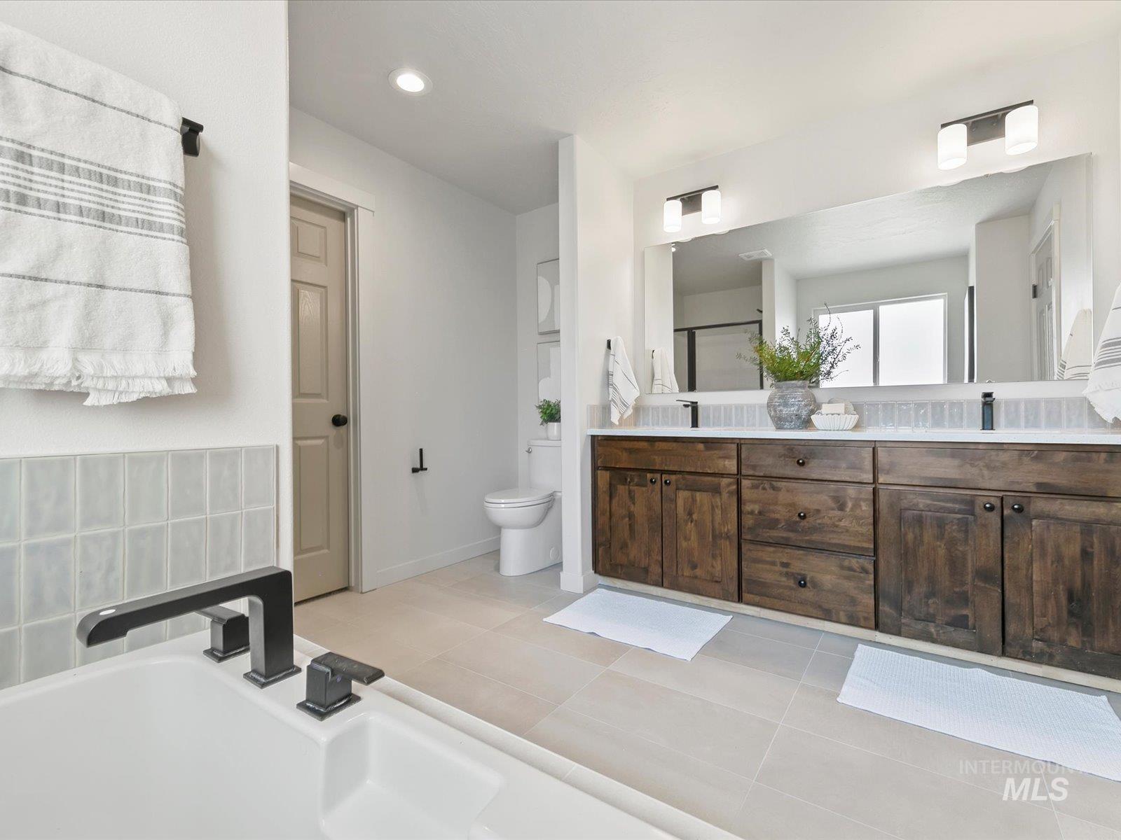 Full bathroom featuring double vanity, light tile patterned floors, a shower stall, recessed lighting, and a garden tub