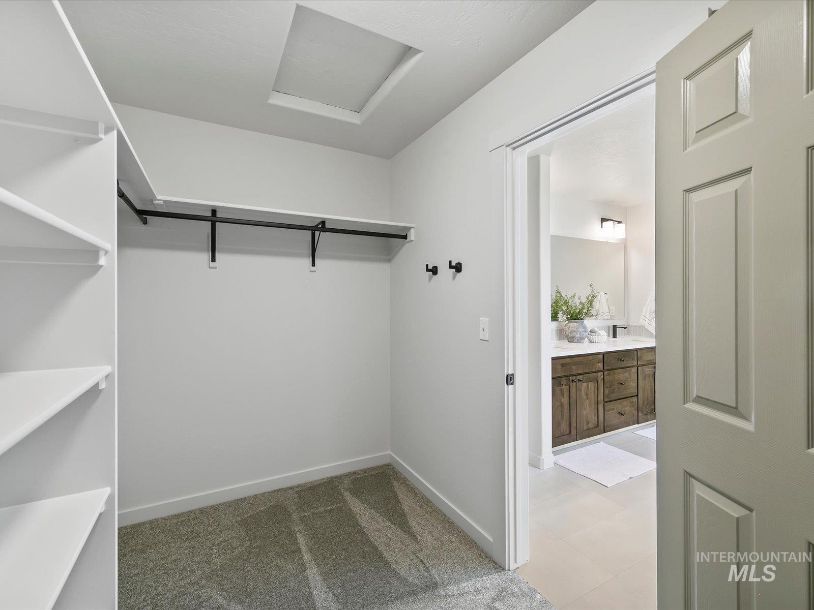 Walk in closet featuring attic access and light carpet