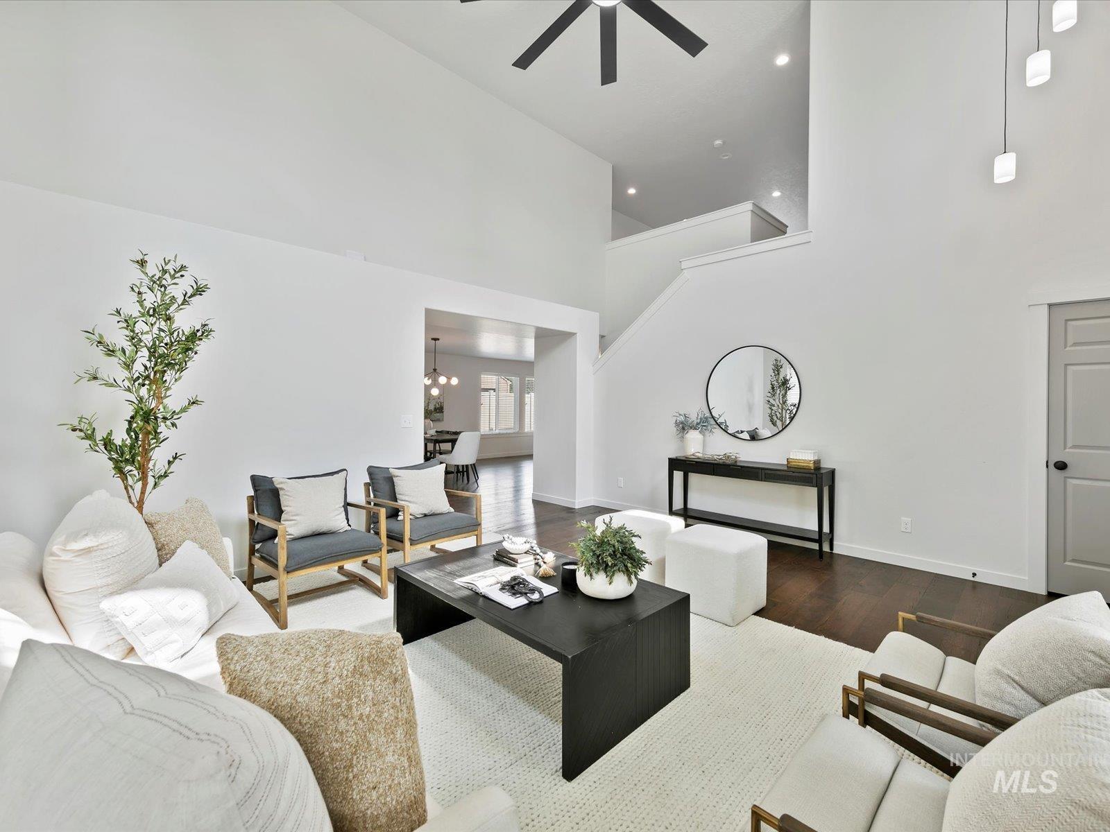 Living area featuring wood finished floors, a towering ceiling, a chandelier, ceiling fan, and recessed lighting