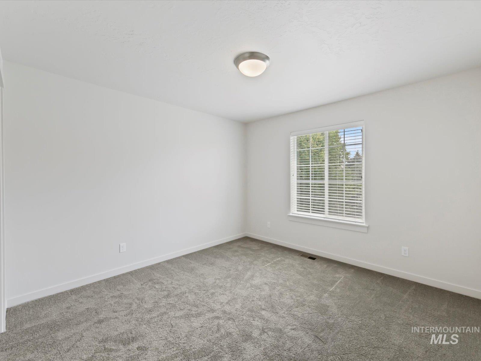 Carpeted empty room featuring baseboards