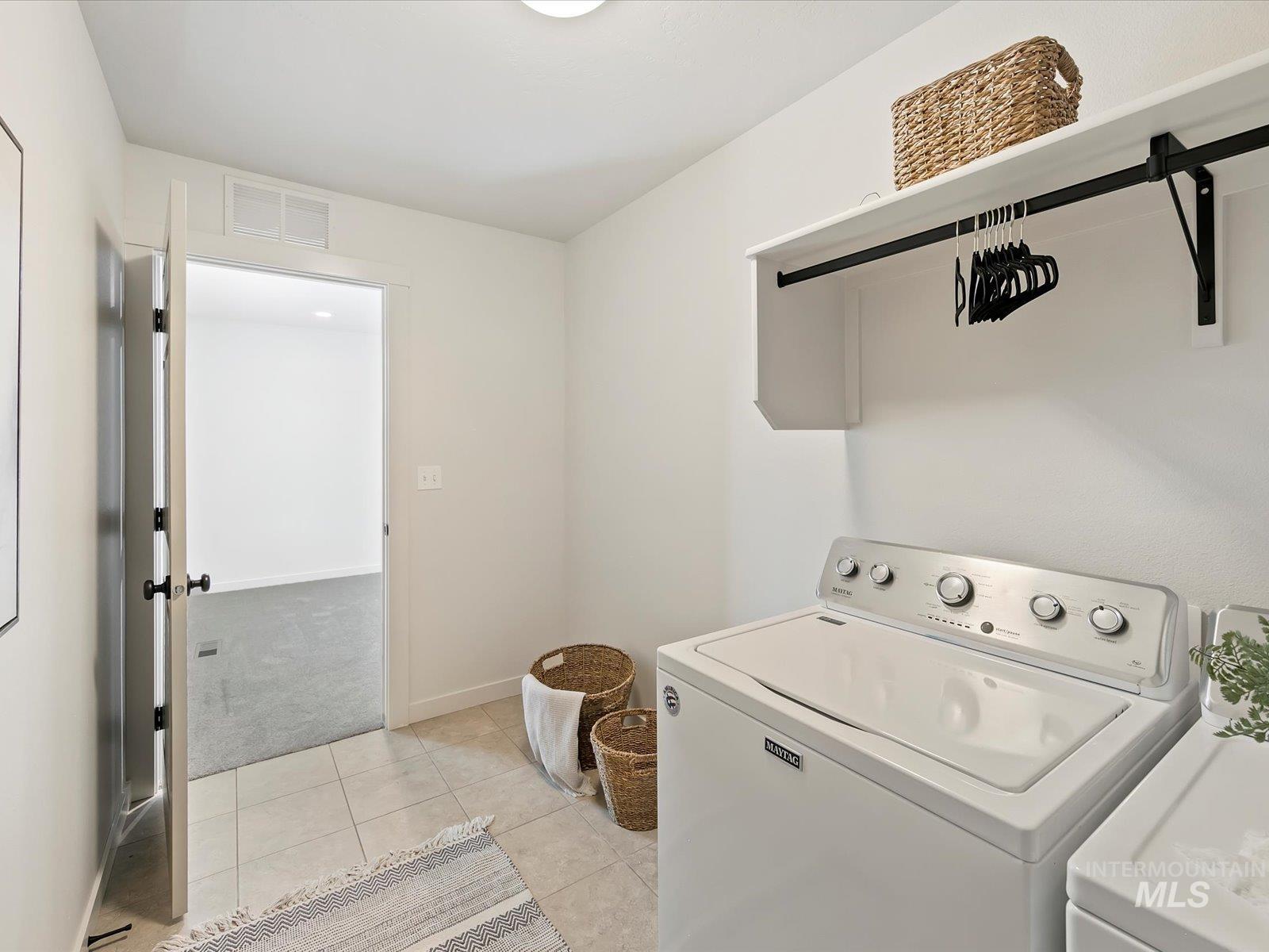 Laundry room with light tile patterned floors, light colored carpet, and separate washer and dryer