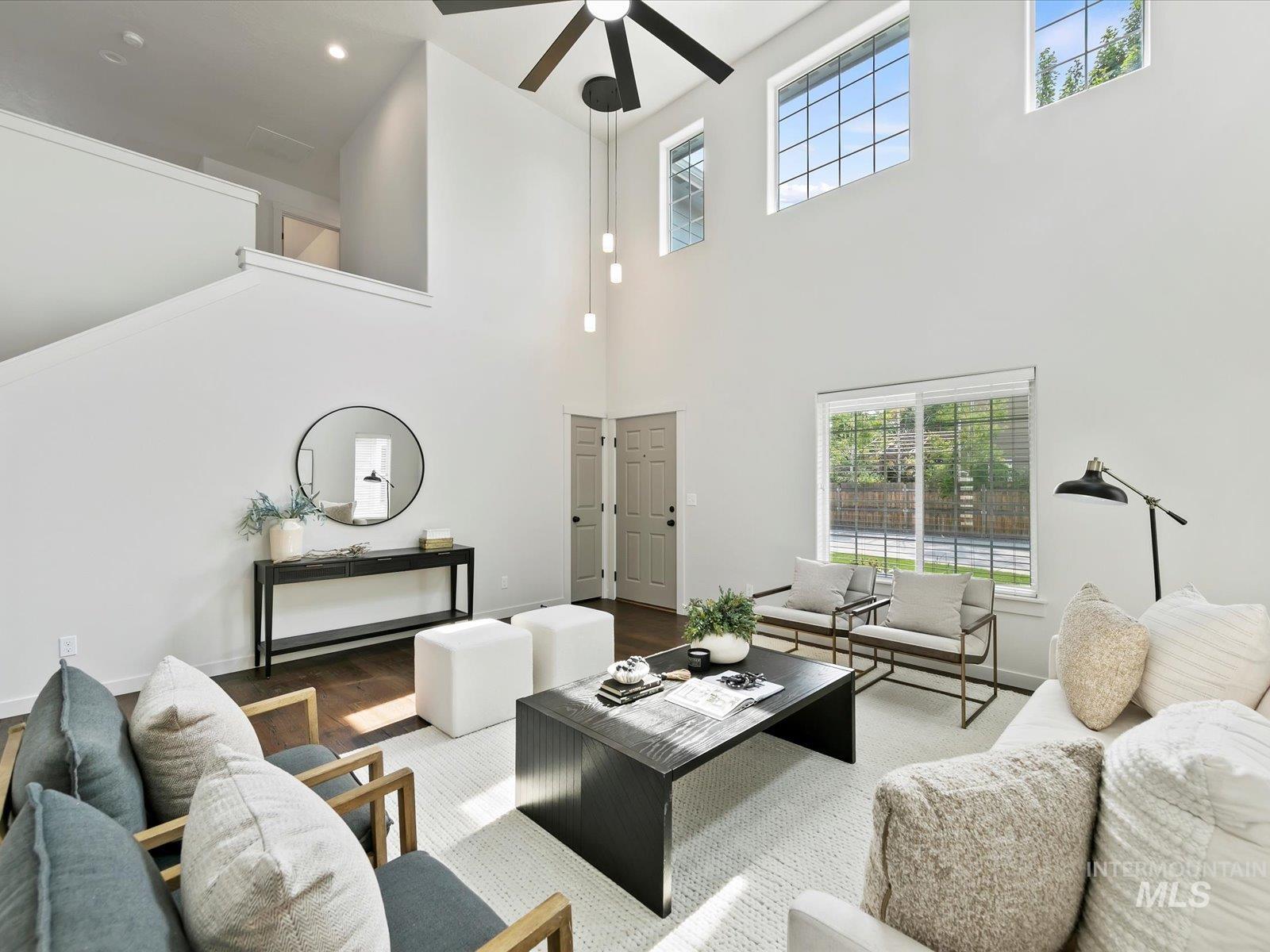 Living room featuring wood finished floors, a towering ceiling, a ceiling fan, and recessed lighting