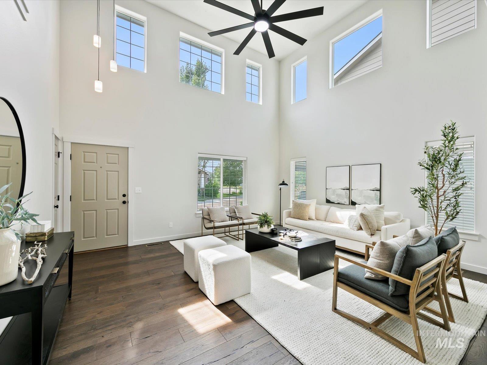 Living area with dark wood finished floors, a high ceiling, and ceiling fan