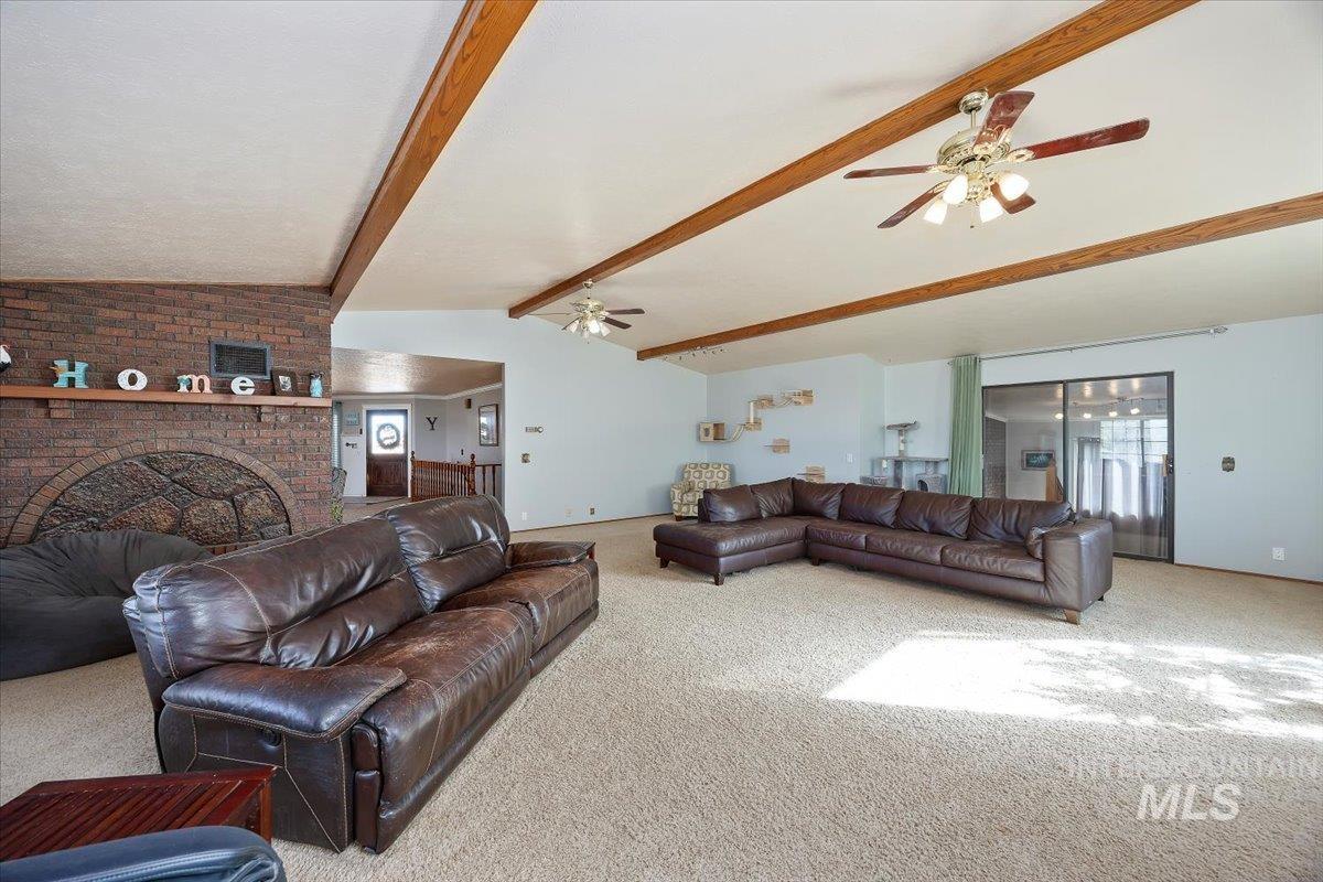 Carpeted living area with a ceiling fan and a brick fireplace