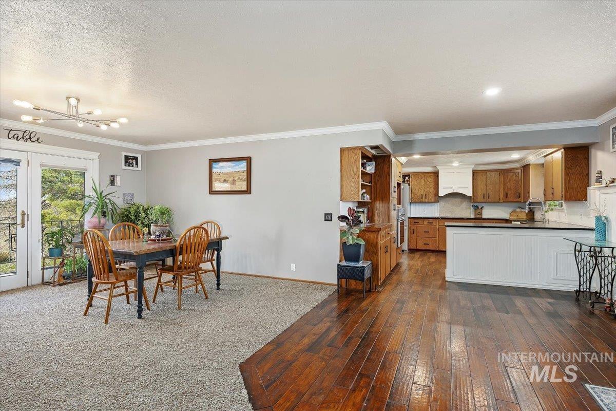 Dining area featuring crown molding, dark wood-type flooring, a chandelier, french doors, and a textured ceiling