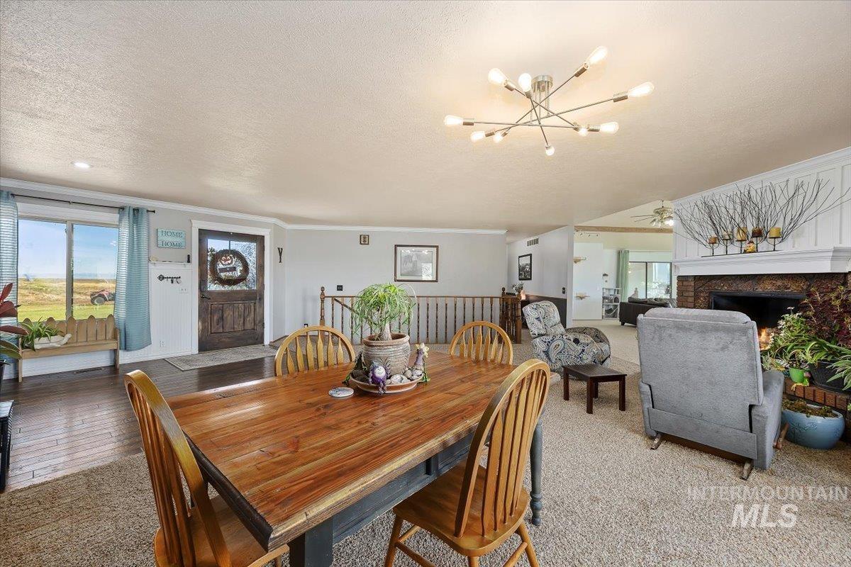 Dining space featuring a textured ceiling, carpet floors, ornamental molding, a fireplace, and a chandelier