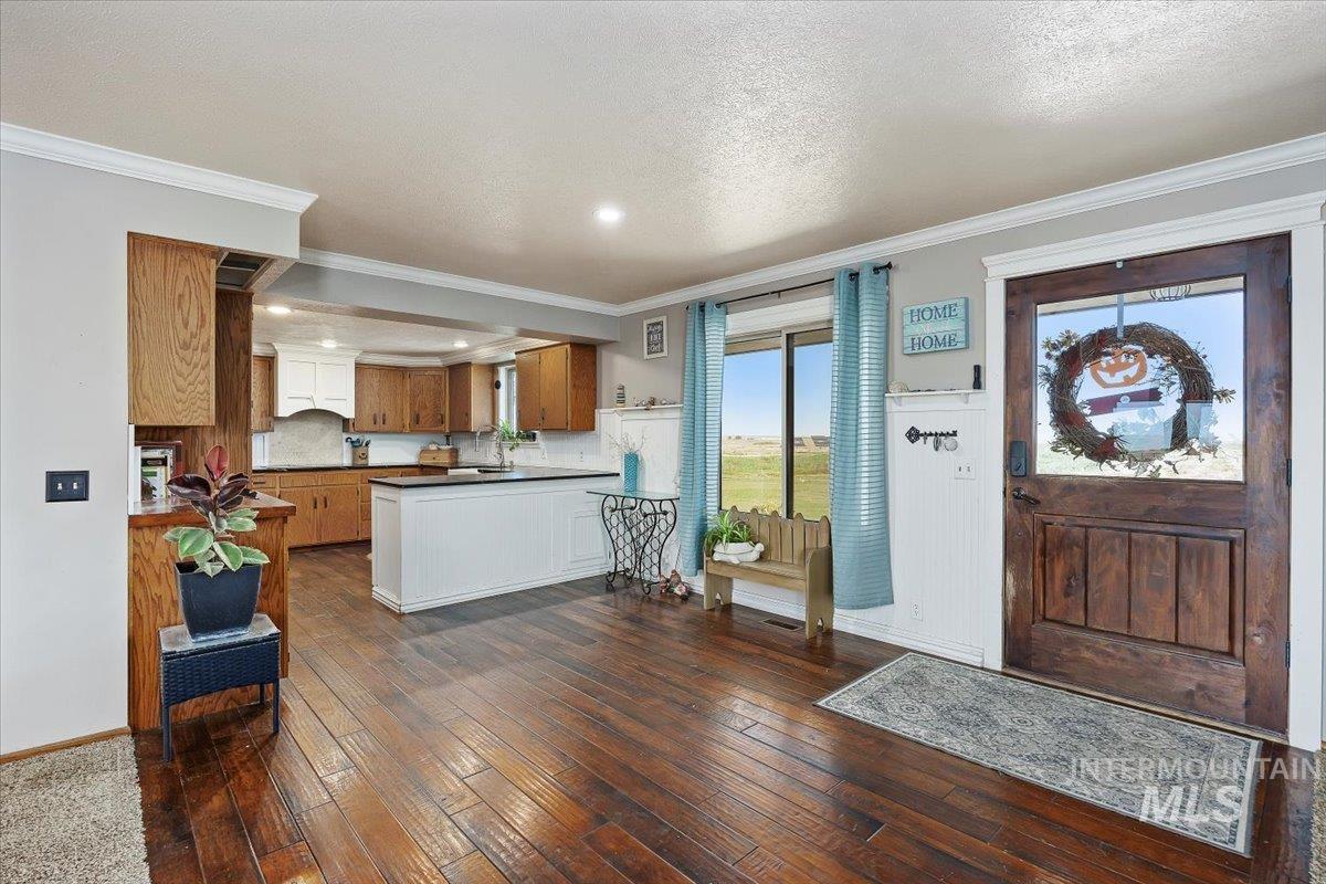 Foyer with dark wood-type flooring, ornamental molding, and a textured ceiling