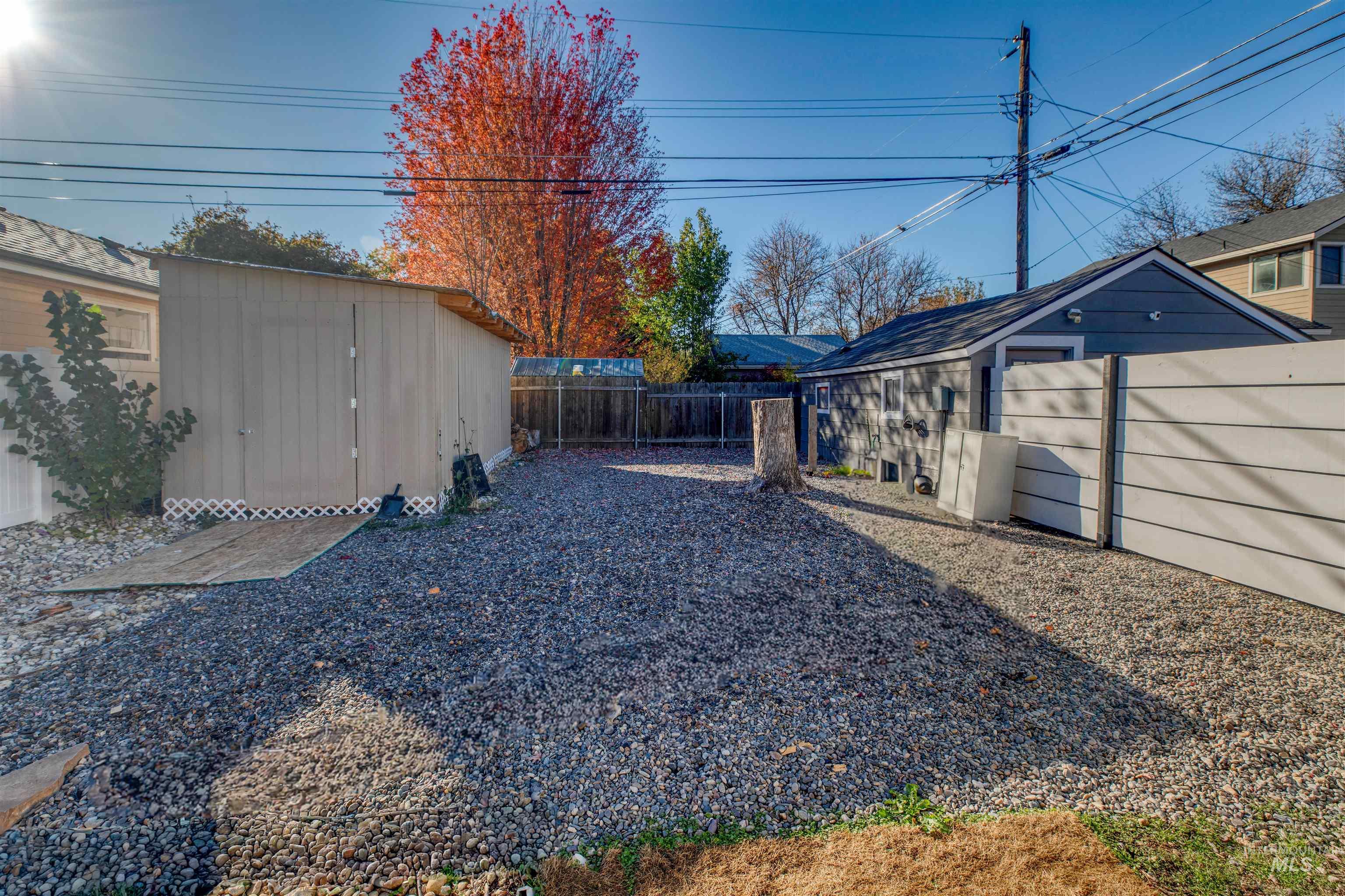 Fenced backyard featuring a storage unit