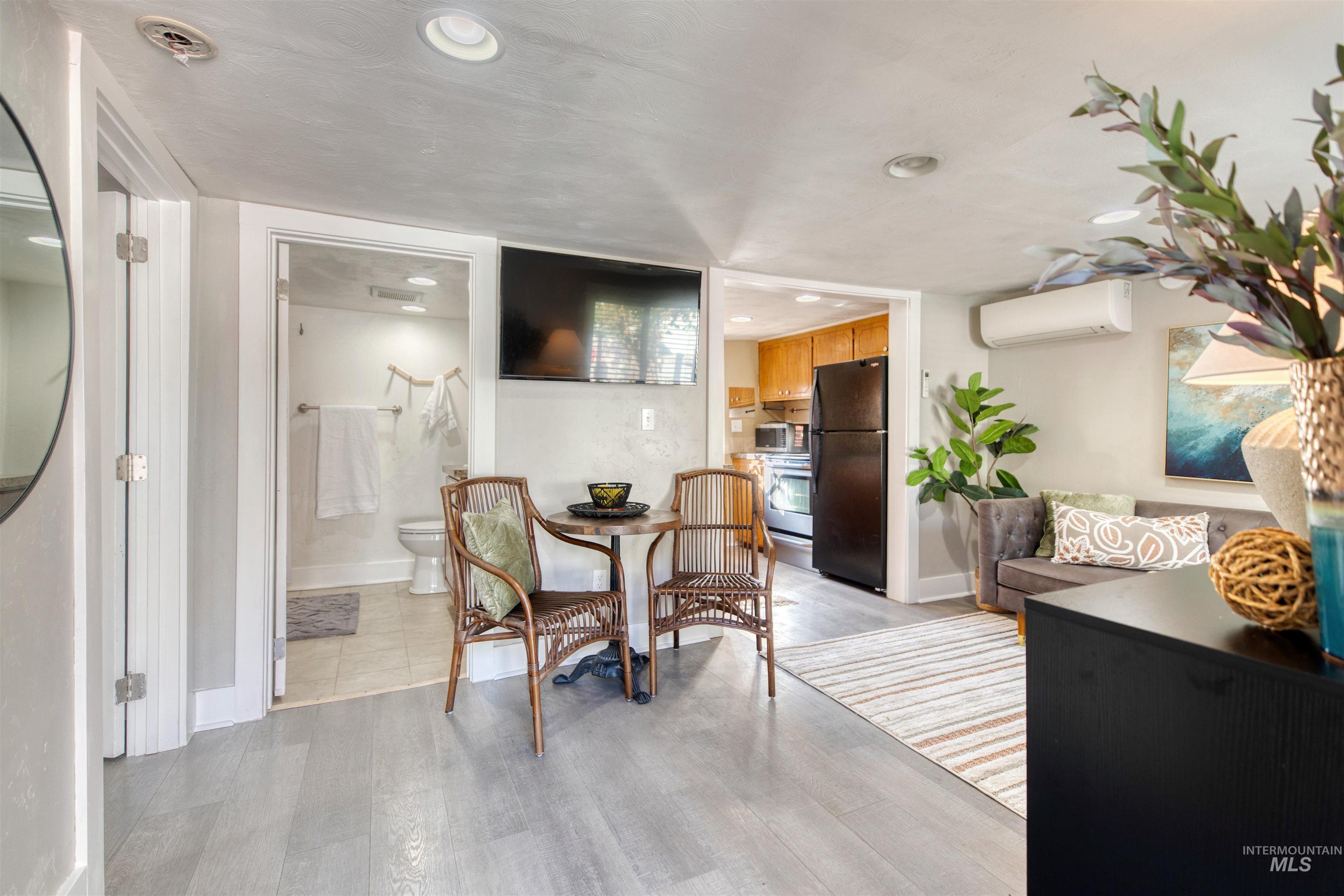 Living area featuring light wood-style flooring, a wall mounted AC, and recessed lighting