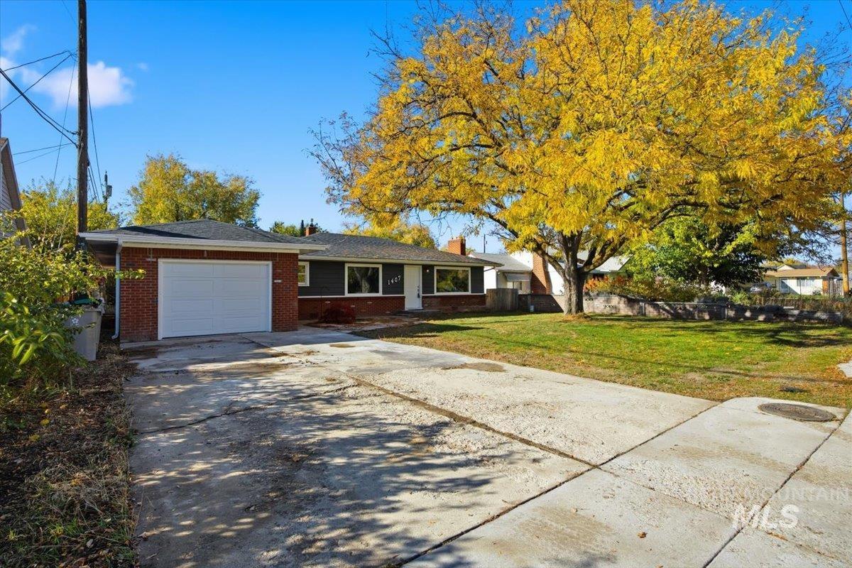 Ranch-style home with a garage, concrete driveway, brick siding, and a chimney
