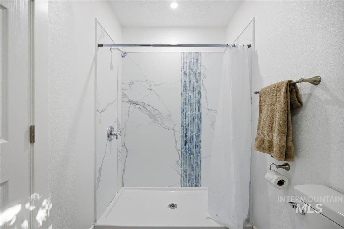 Bathroom with a textured wall and a shower stall