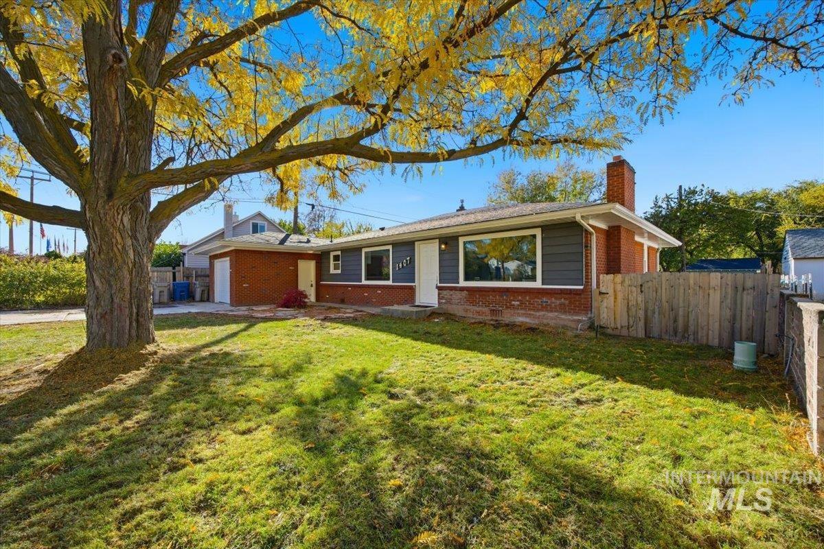 Ranch-style home featuring a chimney, an attached garage, brick siding, and driveway