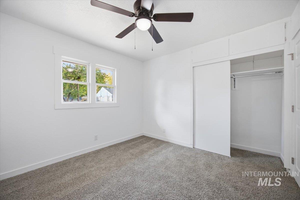 Unfurnished bedroom with a closet, light colored carpet, and a ceiling fan