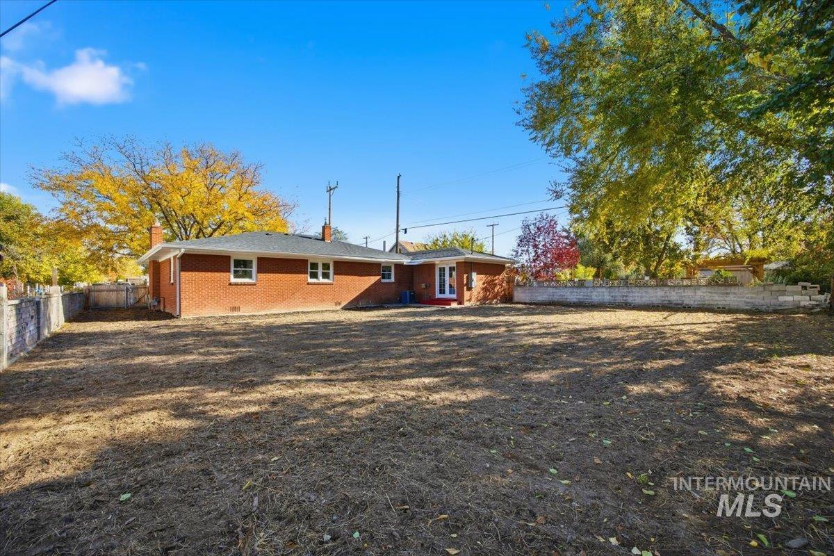 Back of property with a fenced backyard, a chimney, and brick siding