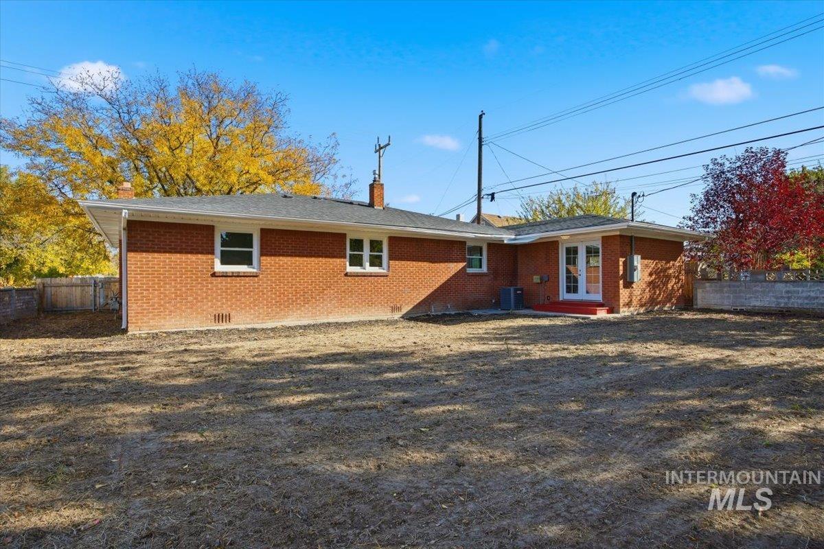 Rear view of property featuring brick siding, a chimney, and crawl space