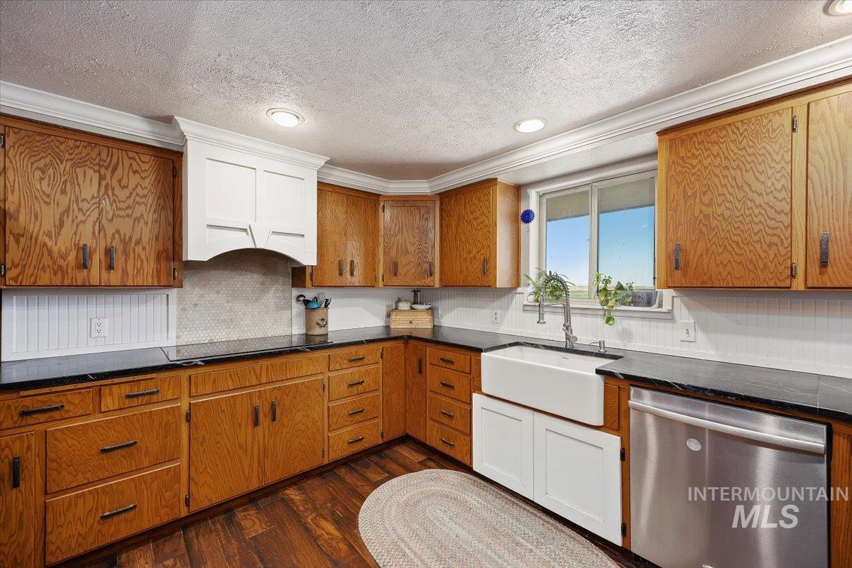 Kitchen featuring dark wood finished floors, brown cabinets, dishwasher, a textured ceiling, and recessed lighting