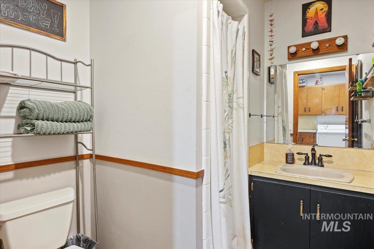 Bathroom with a shower with shower curtain, vanity, and washer / dryer
