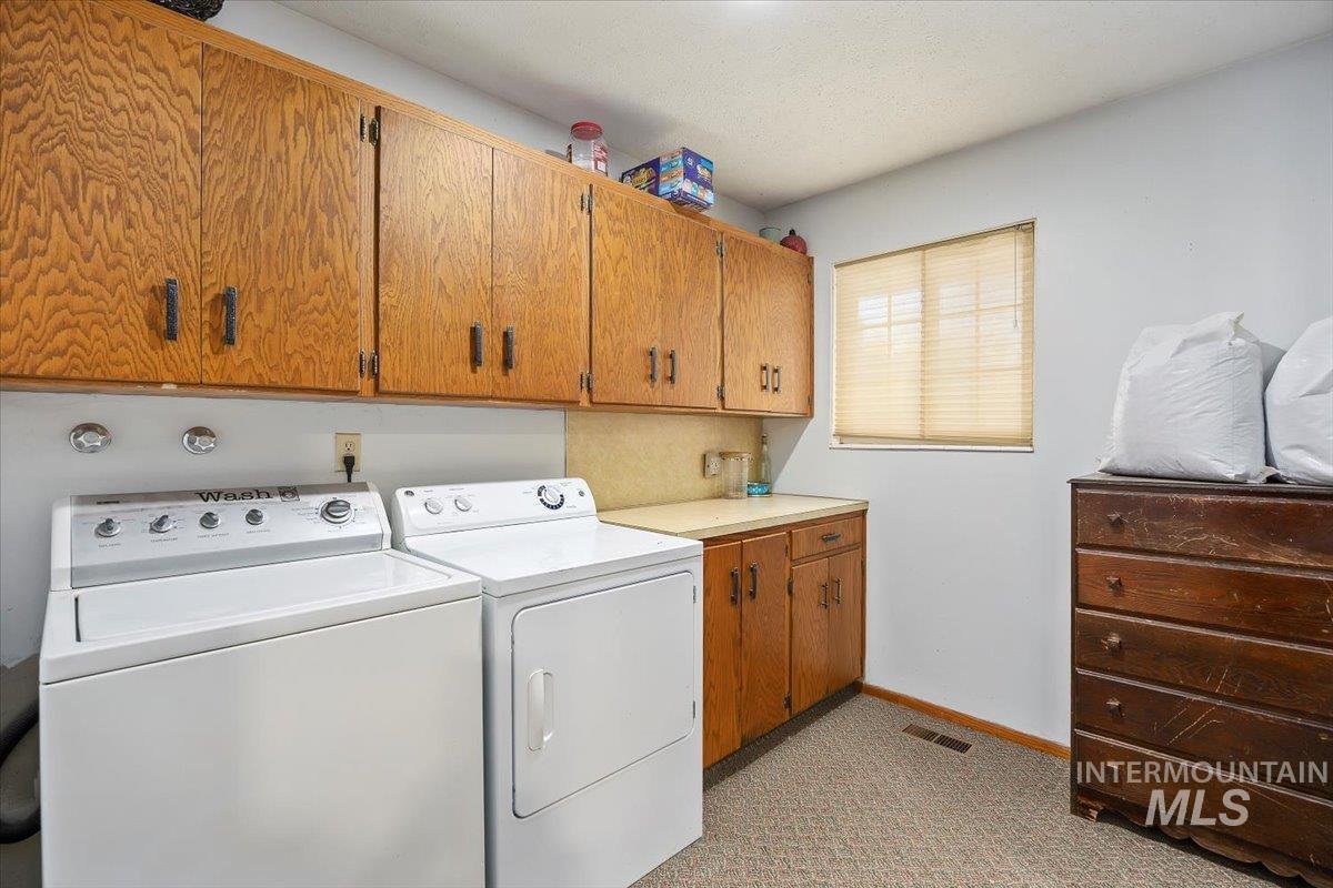 Laundry room featuring cabinet space, washing machine and dryer, and light carpet