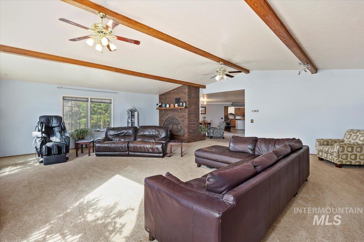 Carpeted living area featuring a ceiling fan and a brick fireplace