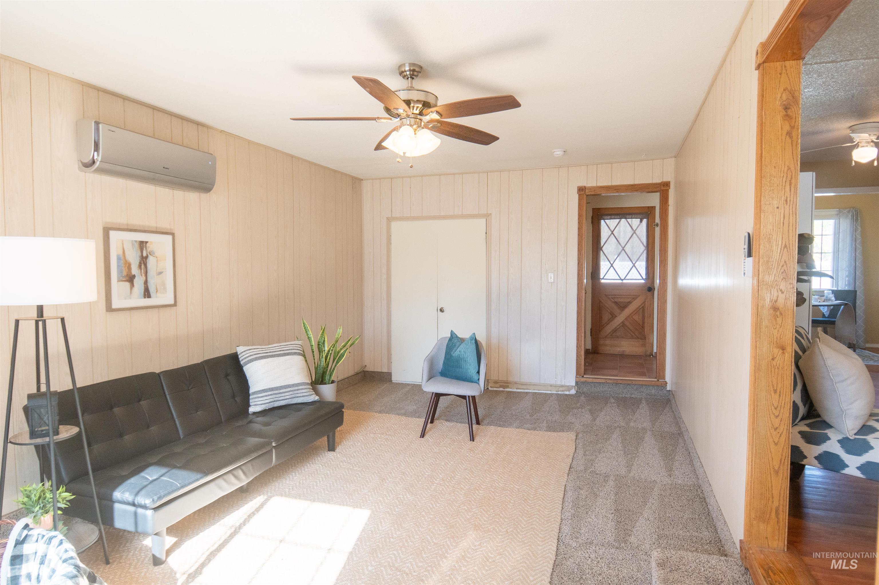 Carpeted living room with ceiling fan, a wall unit AC, and healthy amount of natural light