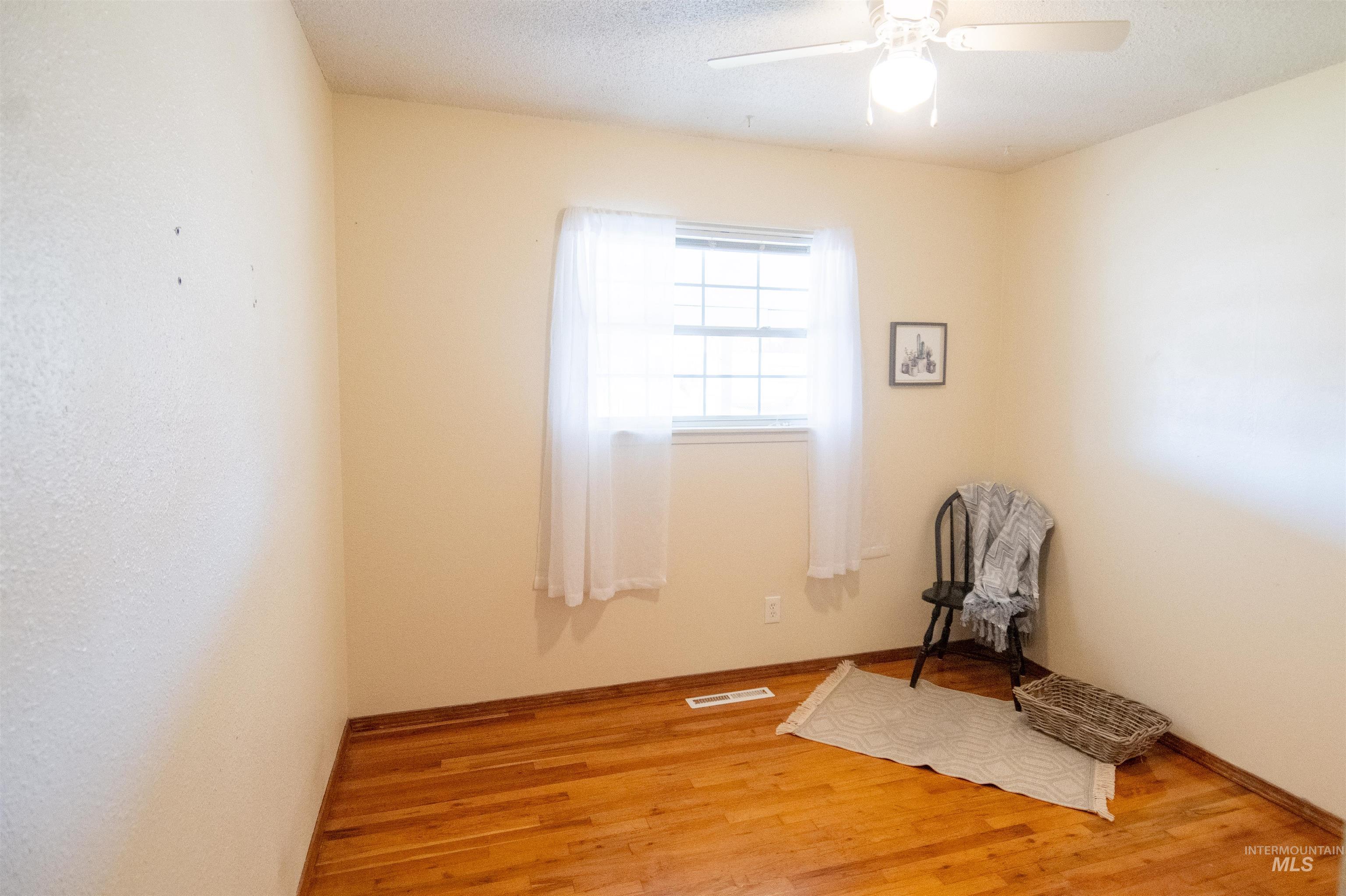 Spare room with light wood-style floors, a textured ceiling, and a ceiling fan