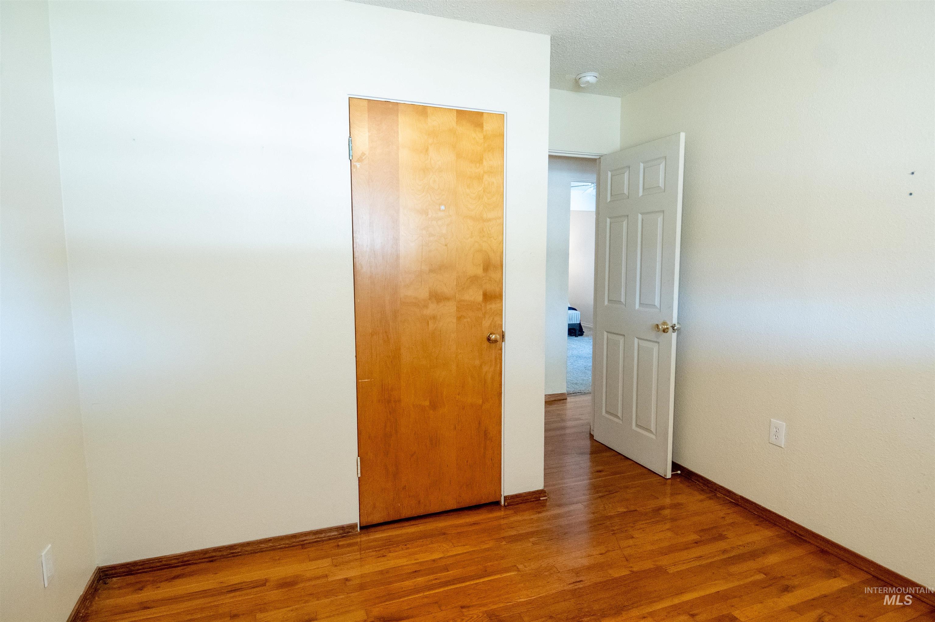 Unfurnished bedroom featuring wood finished floors, a closet, and a textured ceiling