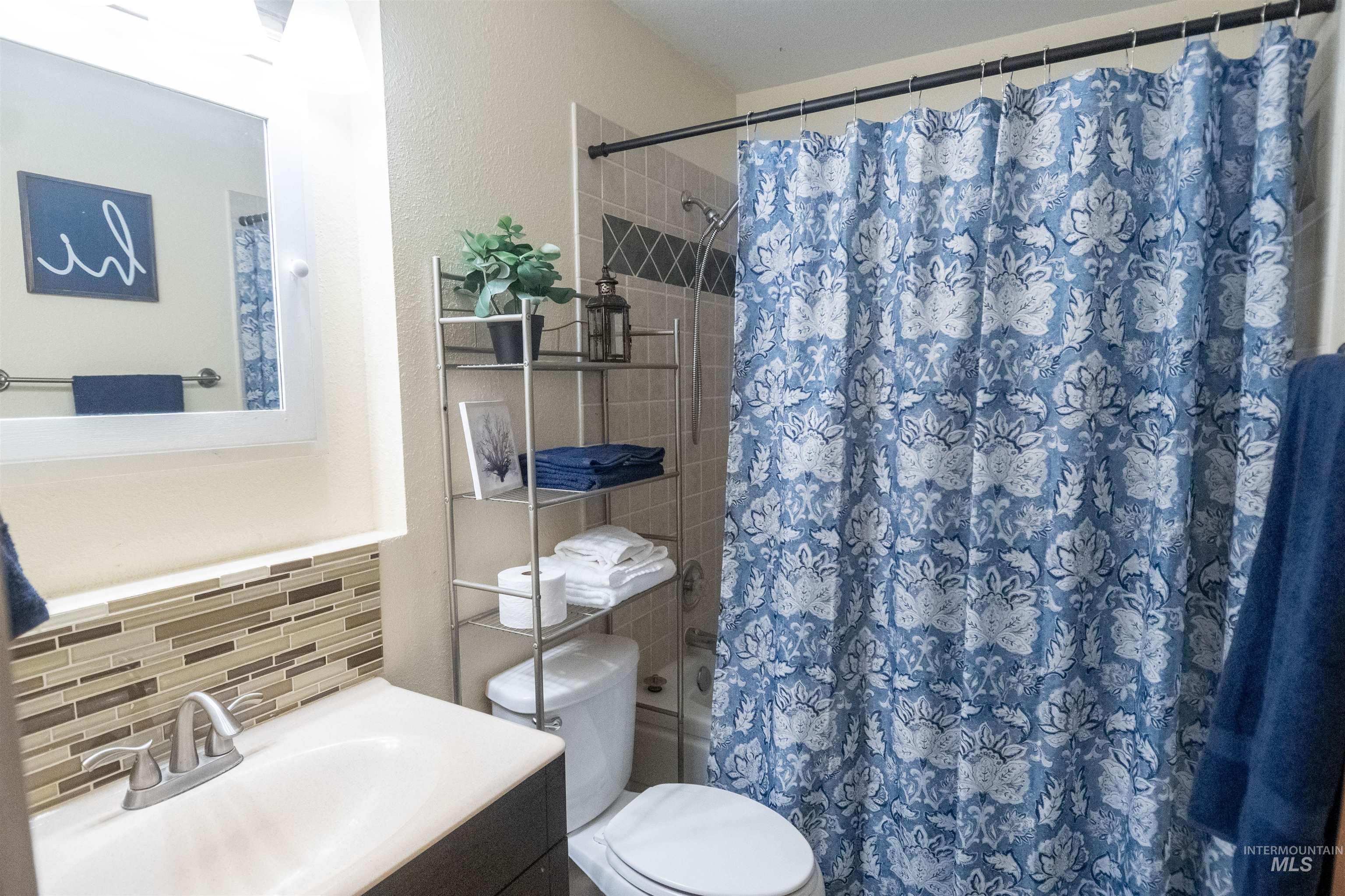 Bathroom with vanity, shower / bath combo, tile walls, and tasteful backsplash