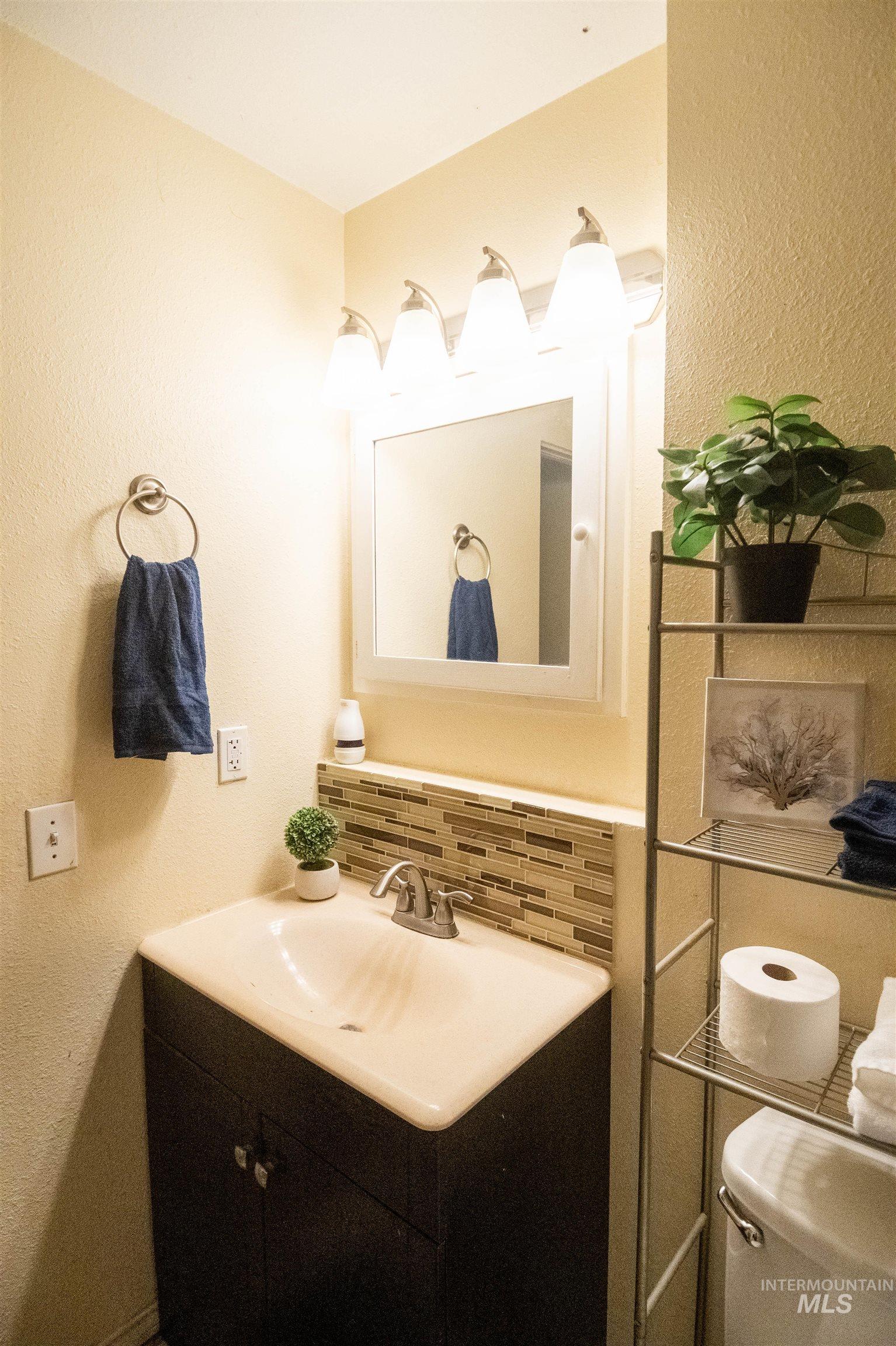 Half bathroom featuring a textured wall, tasteful backsplash, and vanity