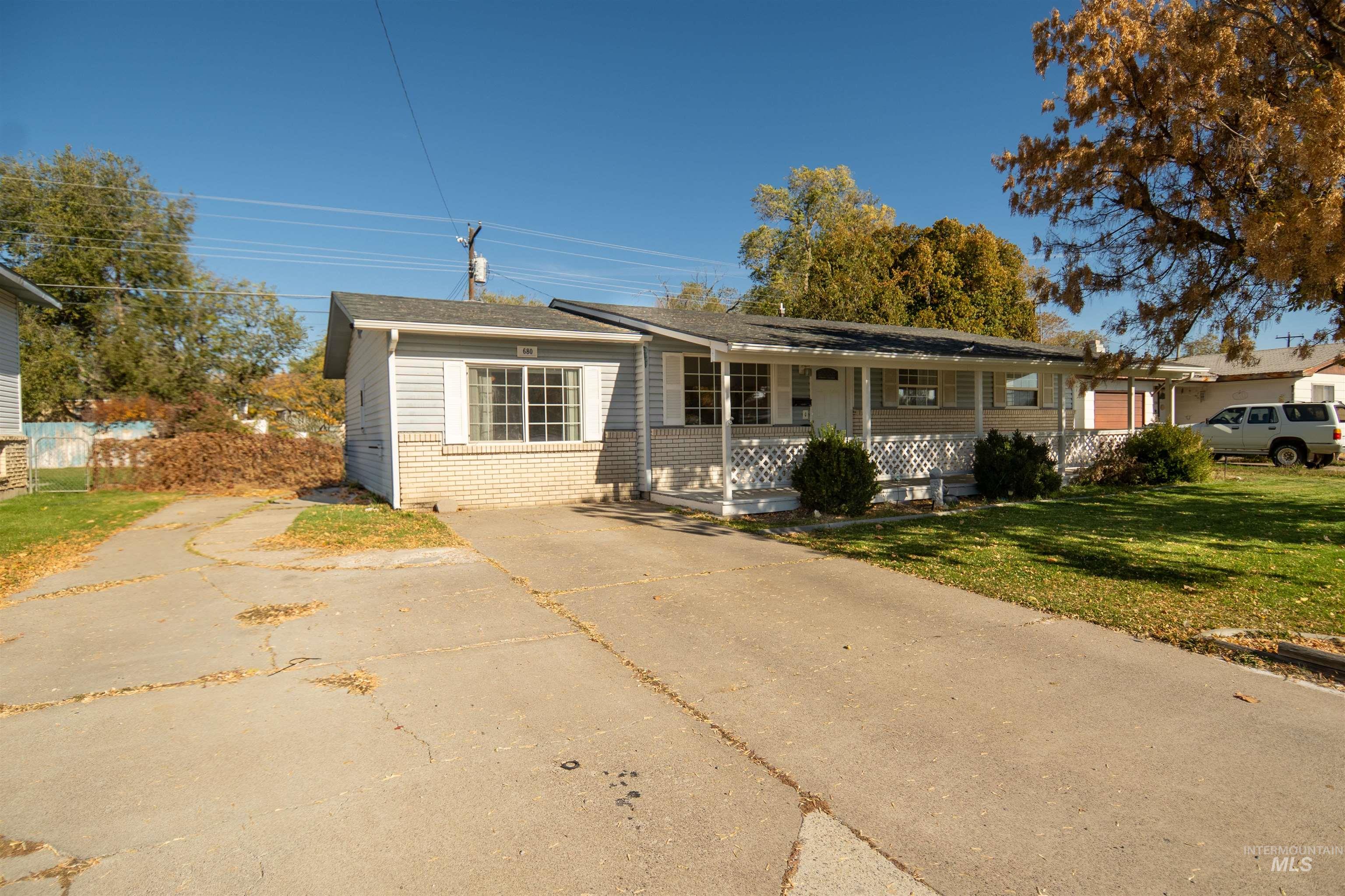 Ranch-style home with brick siding, covered porch, a front lawn, and driveway