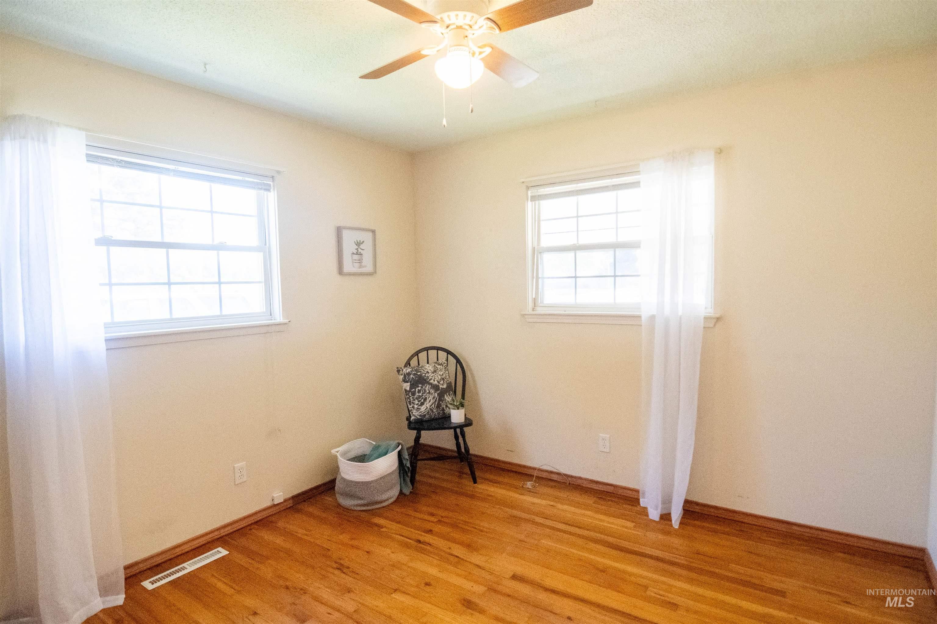 Unfurnished room with healthy amount of natural light, light wood-style flooring, and ceiling fan