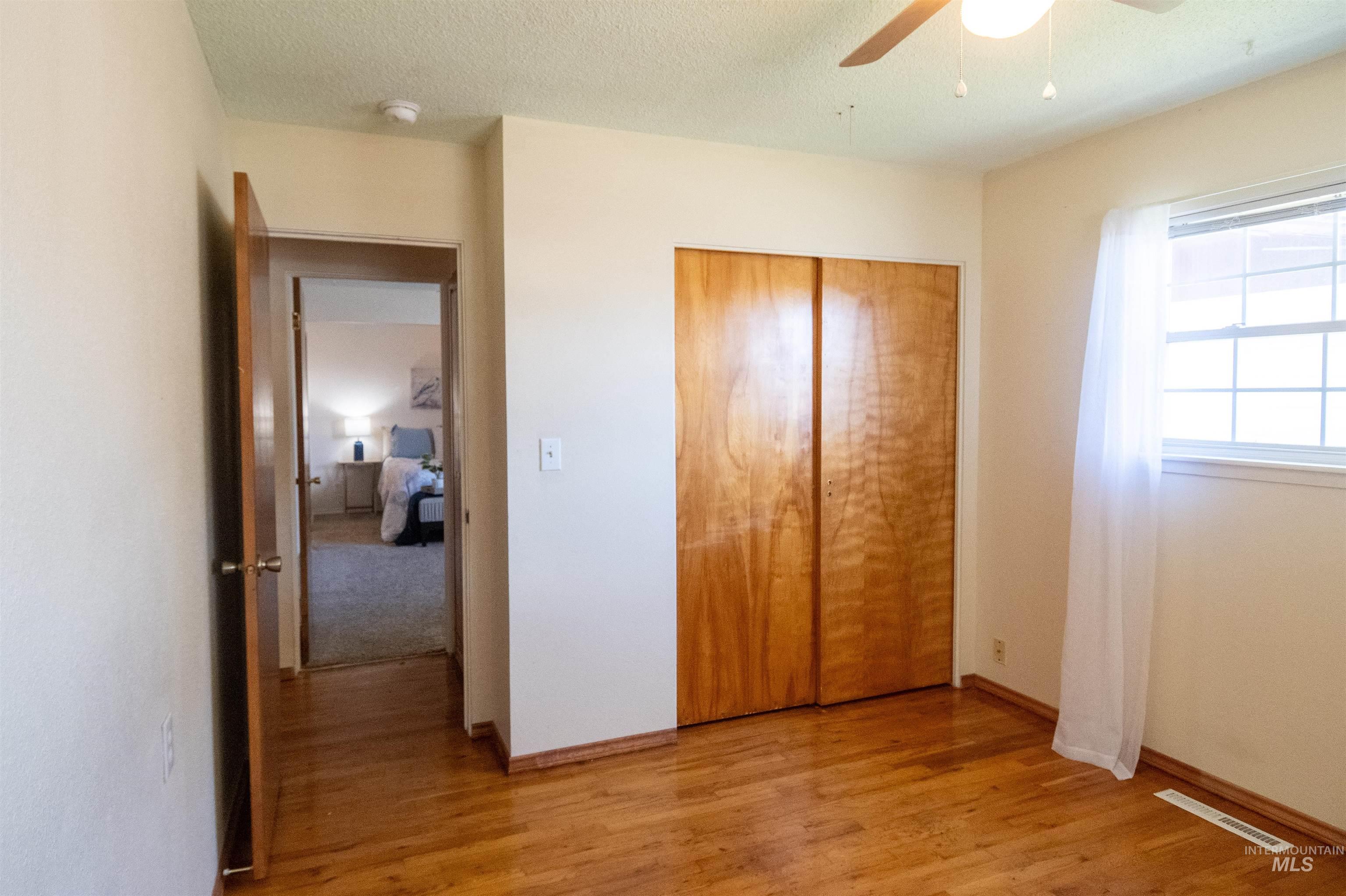 Unfurnished bedroom featuring light wood-style flooring, a closet, ceiling fan, and a textured ceiling