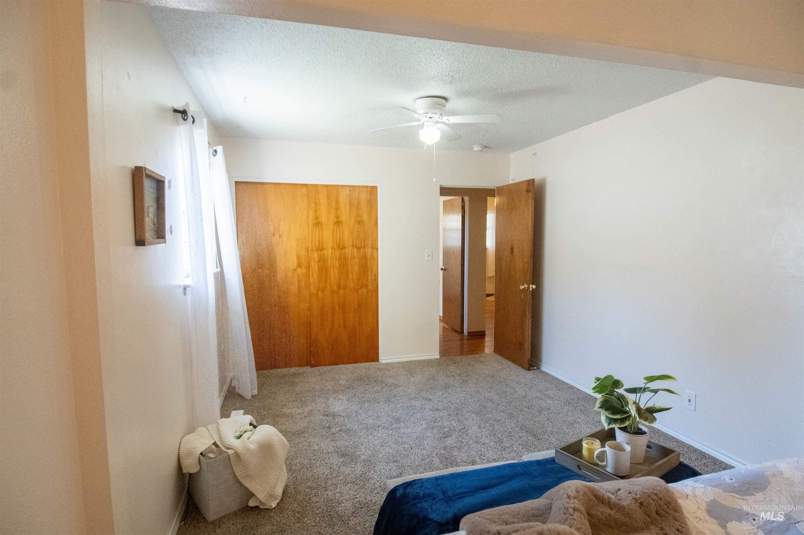 Carpeted bedroom with a closet, ceiling fan, and a textured ceiling