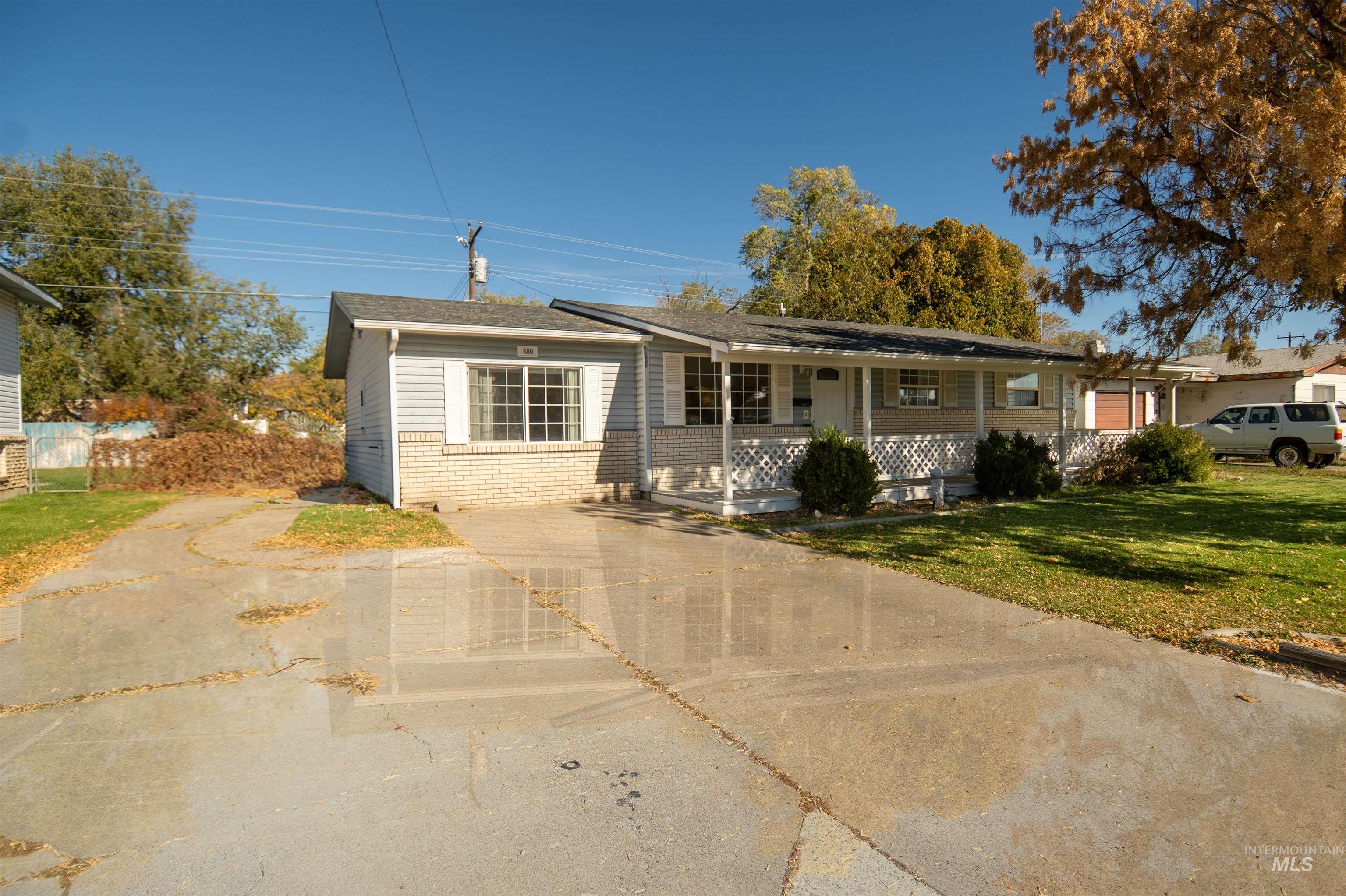 Single story home featuring brick siding, a porch, a front lawn, and driveway