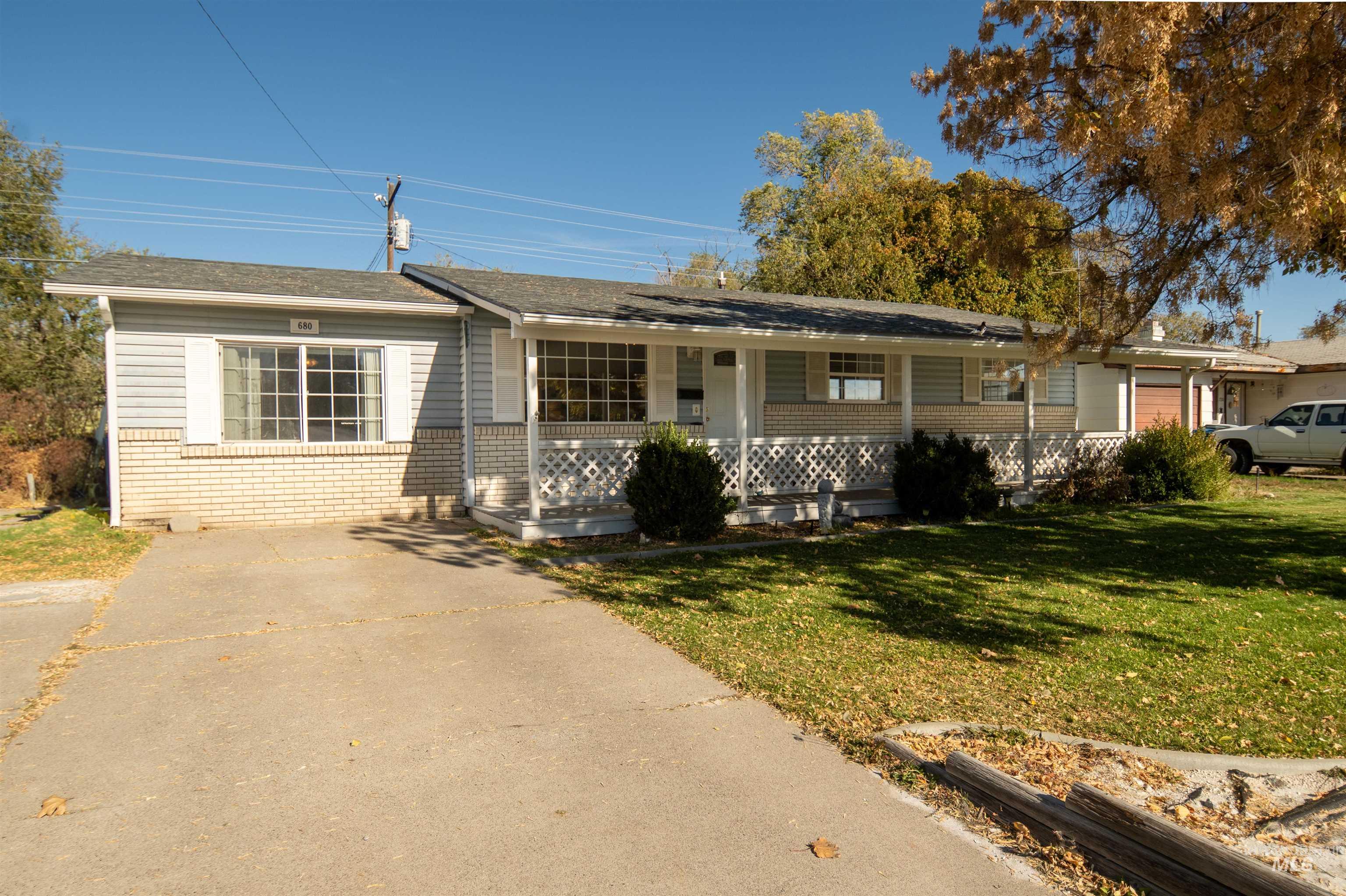 Single story home featuring a porch, brick siding, and a front lawn