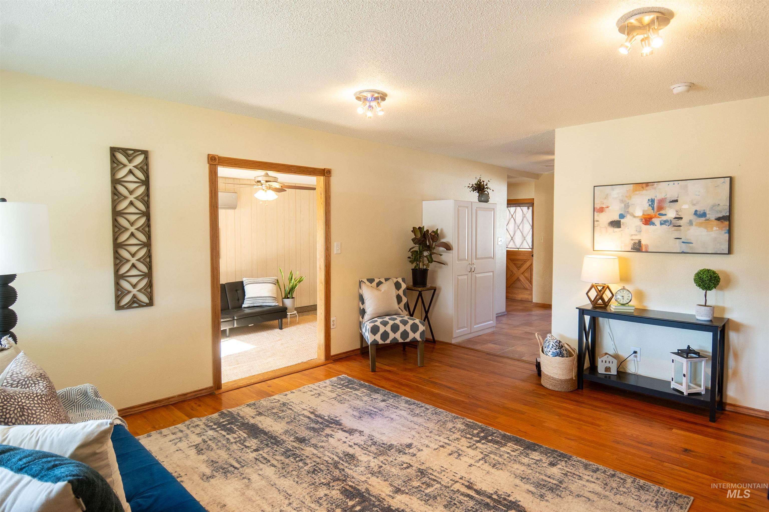 Living room with light wood-style flooring, a textured ceiling, and ceiling fan