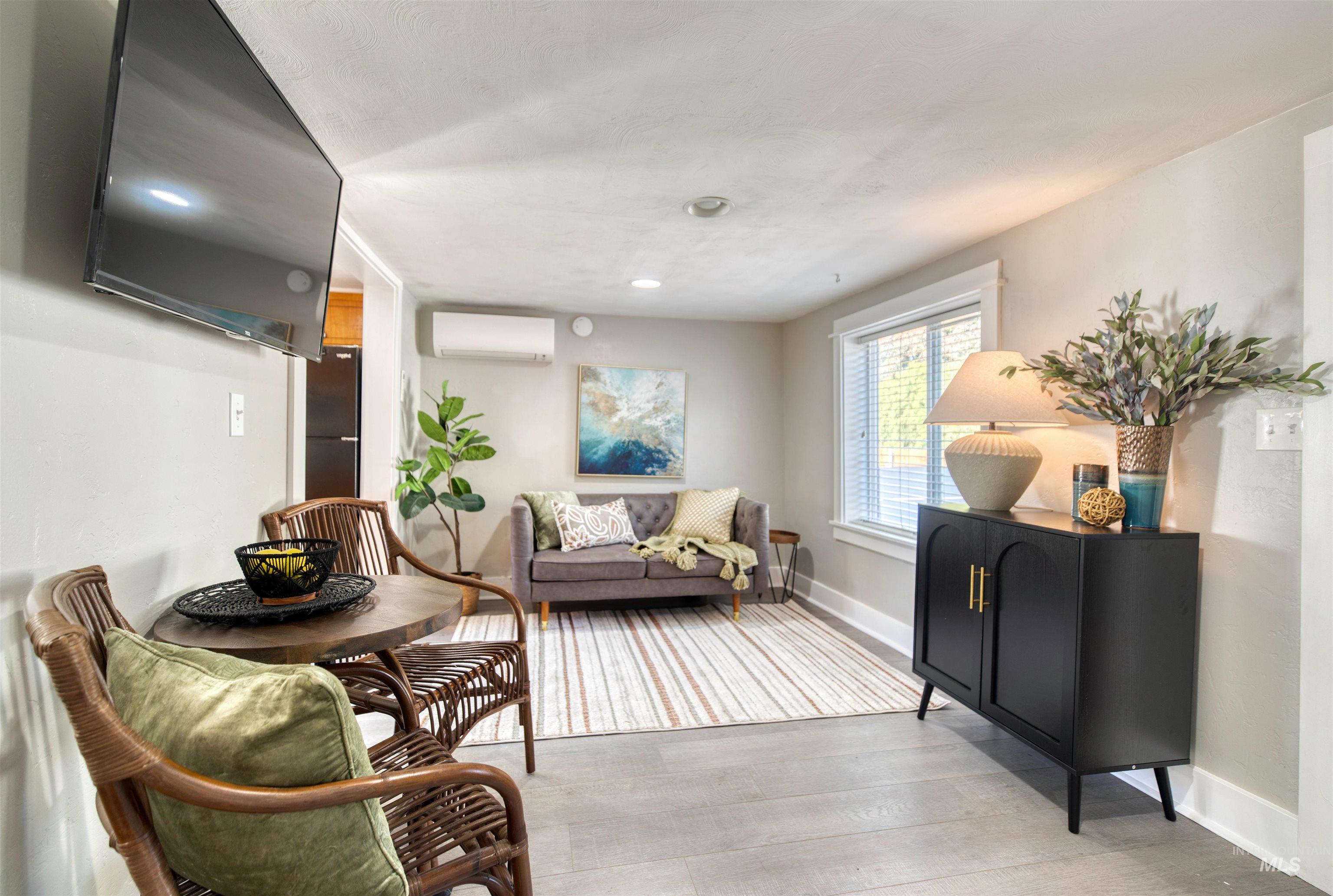 Living room featuring light wood-type flooring and a wall unit AC