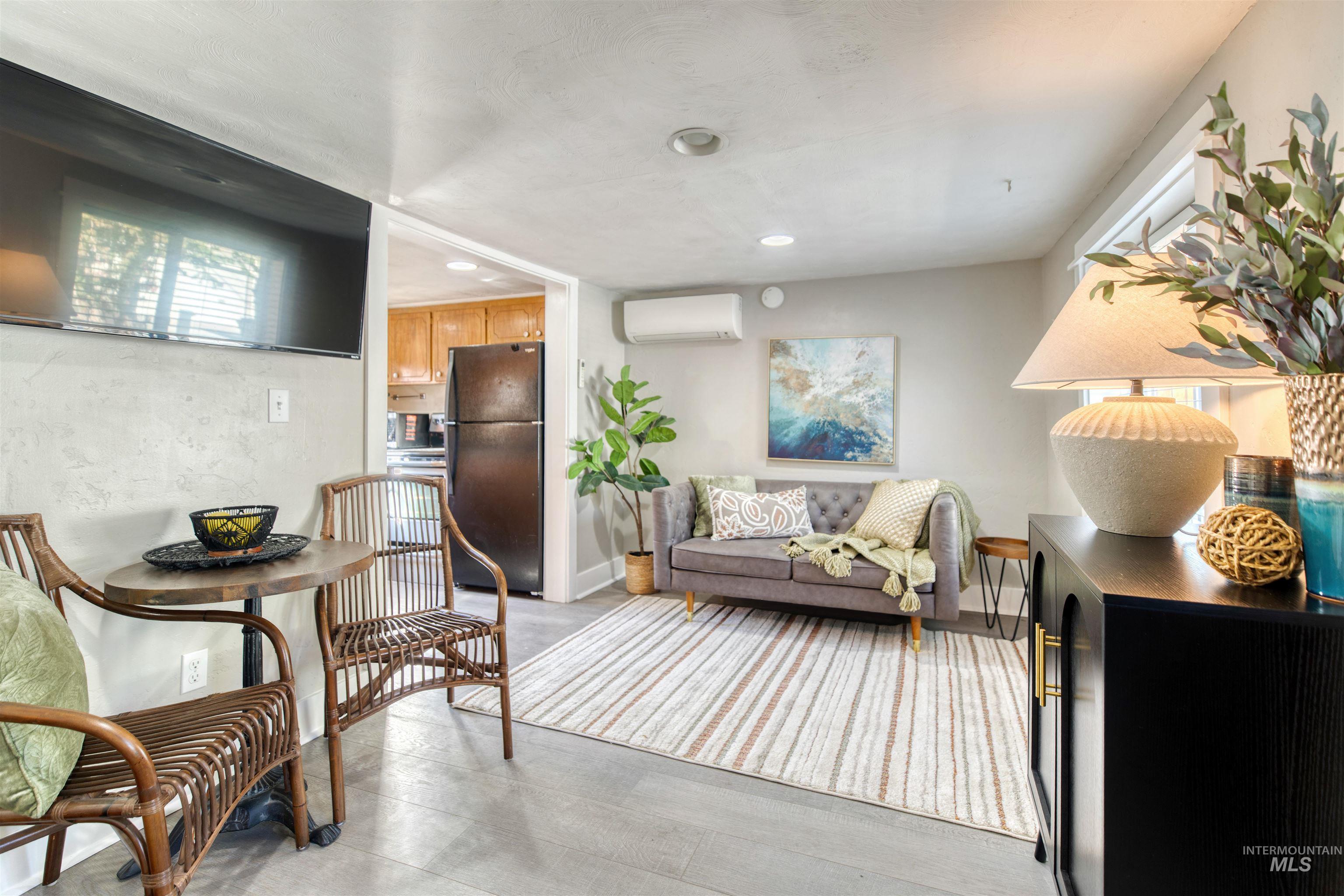 Living room featuring a wall mounted AC, recessed lighting, and light wood-style flooring