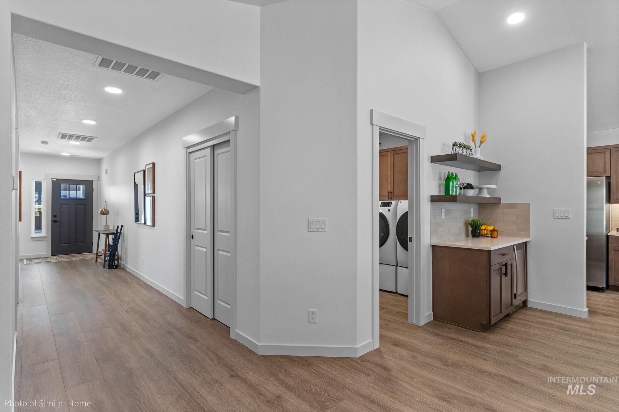 Hallway with recessed lighting, light wood-type flooring, and independent washer and dryer