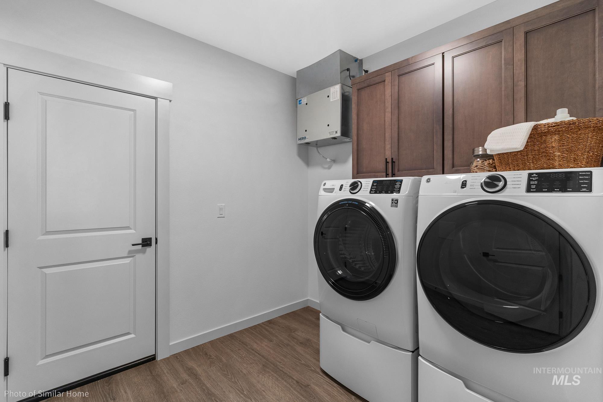 Laundry area with wood finished floors, independent washer and dryer, and cabinet space