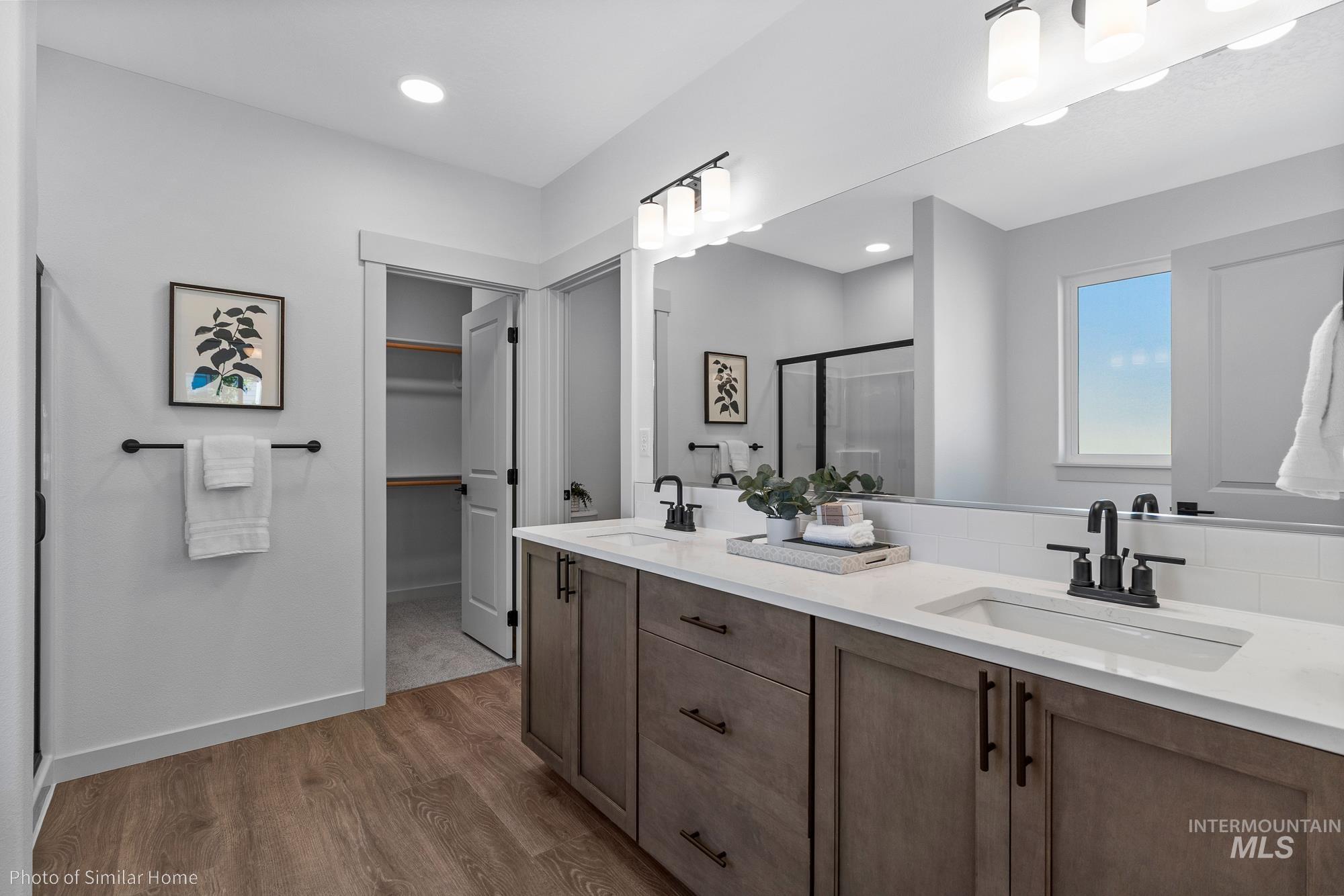 Full bathroom featuring a stall shower, double vanity, a spacious closet, light wood-type flooring, and recessed lighting