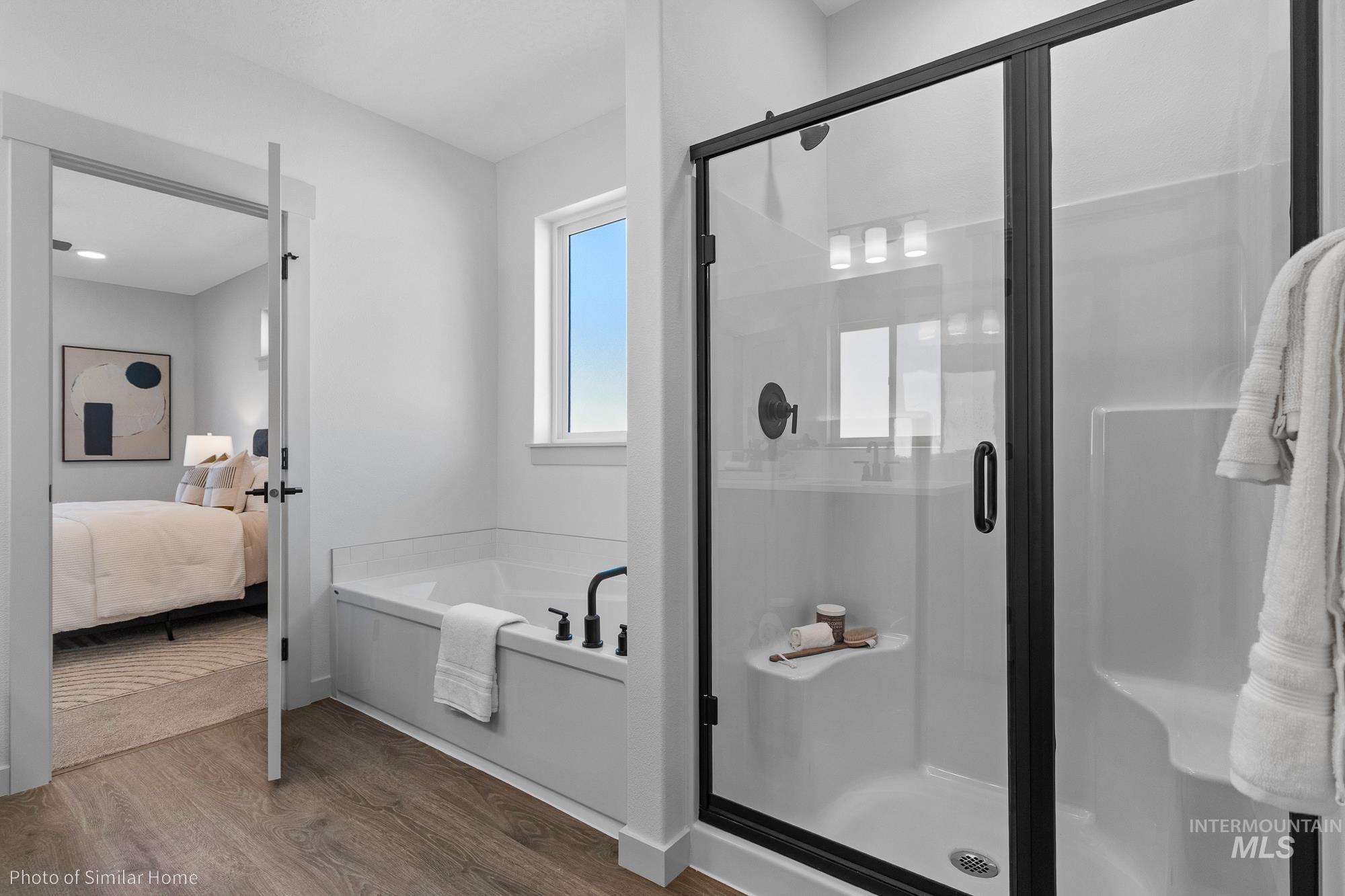 Ensuite bathroom featuring wood finished floors, a bath, and a shower stall
