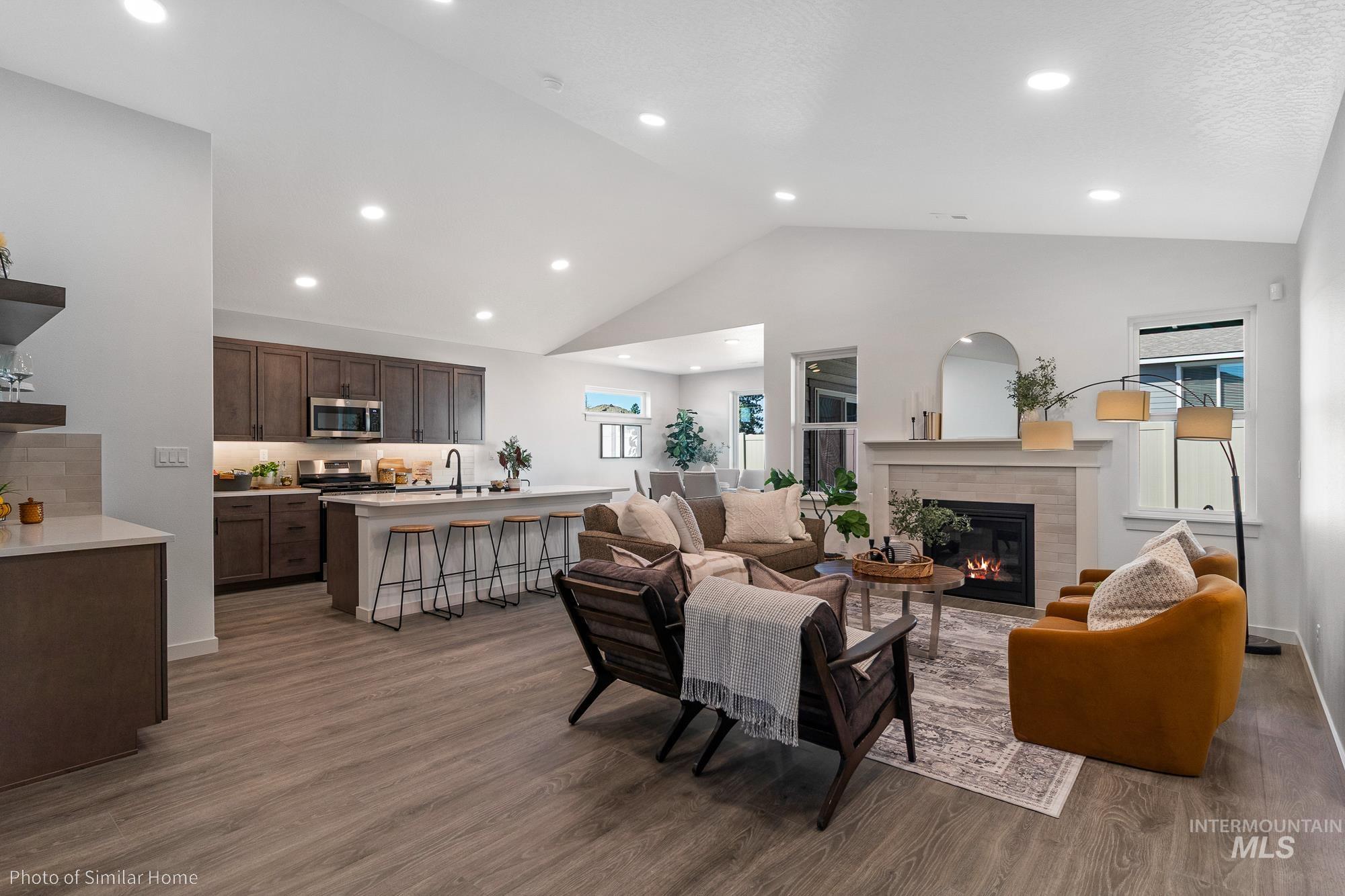 Living room with dark wood-style floors, recessed lighting, a fireplace, and high vaulted ceiling